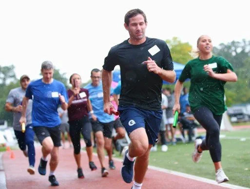 Group of people running on track during a relay  race.
