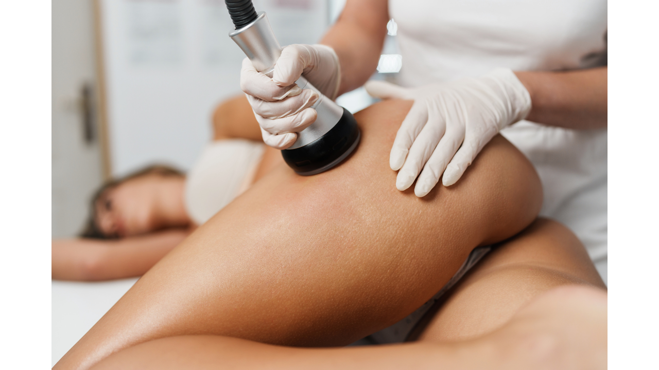 A person receiving a massage with a massage gun on their thigh, lying on a massage table with another person lying nearby.
