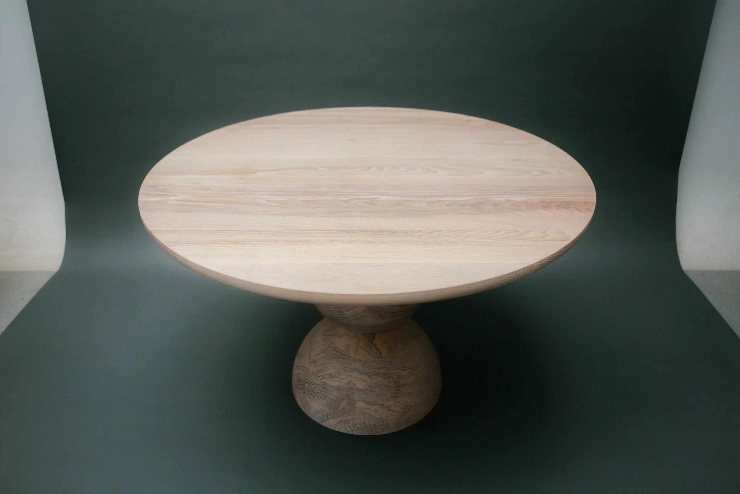 Mesa de madera redonda en un fondo oscuro.