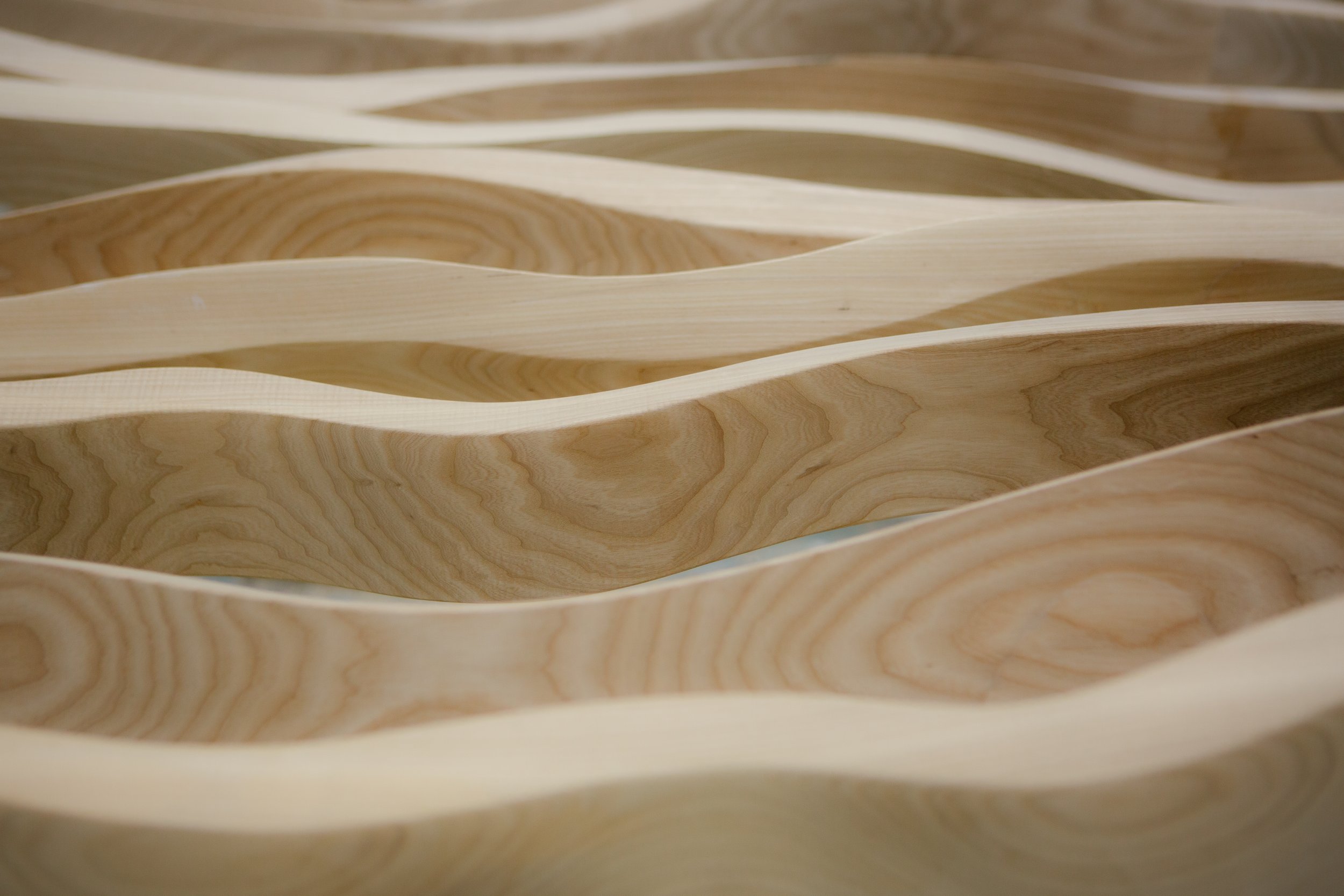 Estructura de madera con formas curvas y ondas, con vetas de la madera visibles en tonos claros y oscuros.