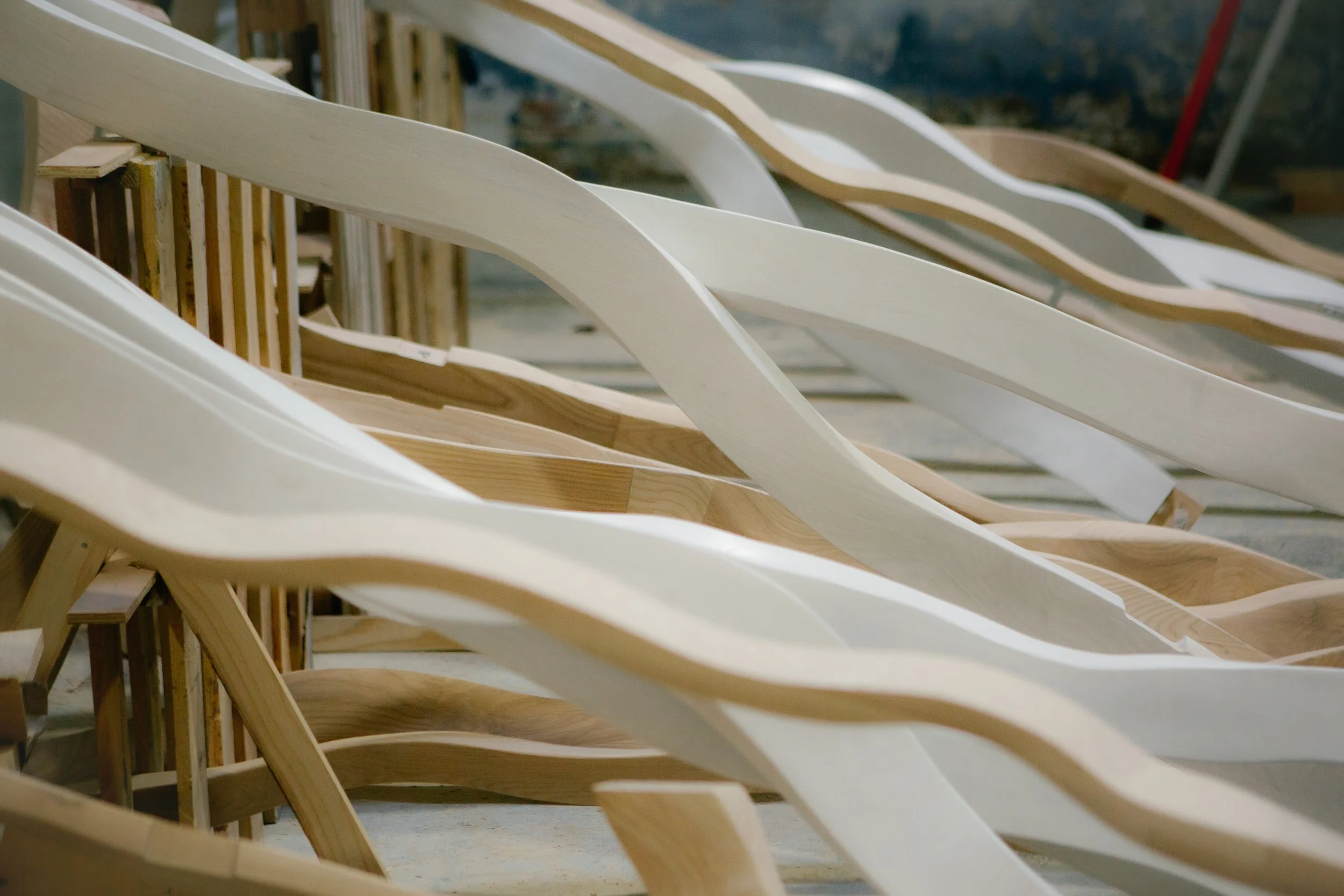 Filas de sillas de madera sin terminar en un taller de carpintería.