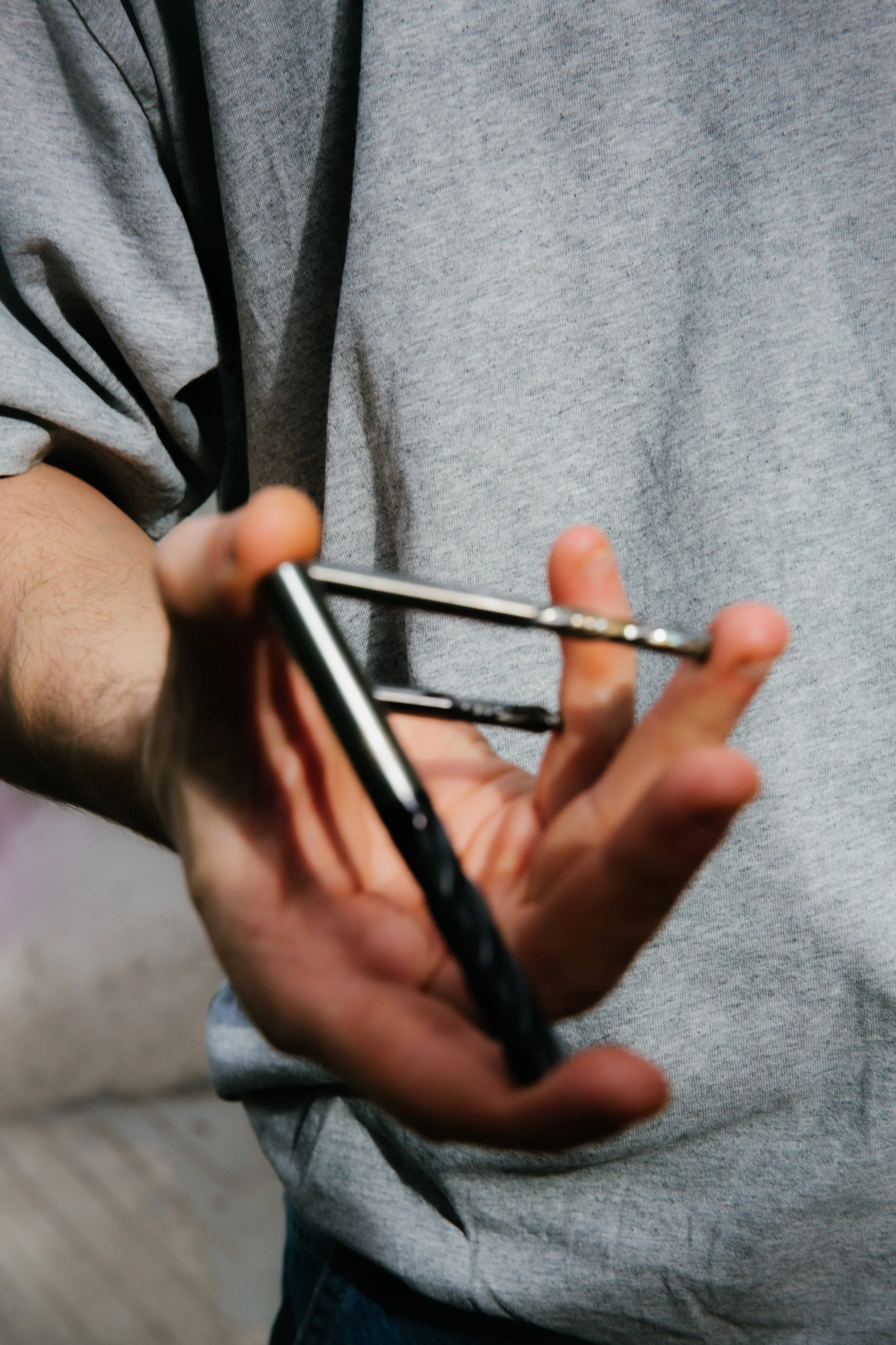 Persona usando camisa gris y sosteniendo un teléfono celular con ambas manos.