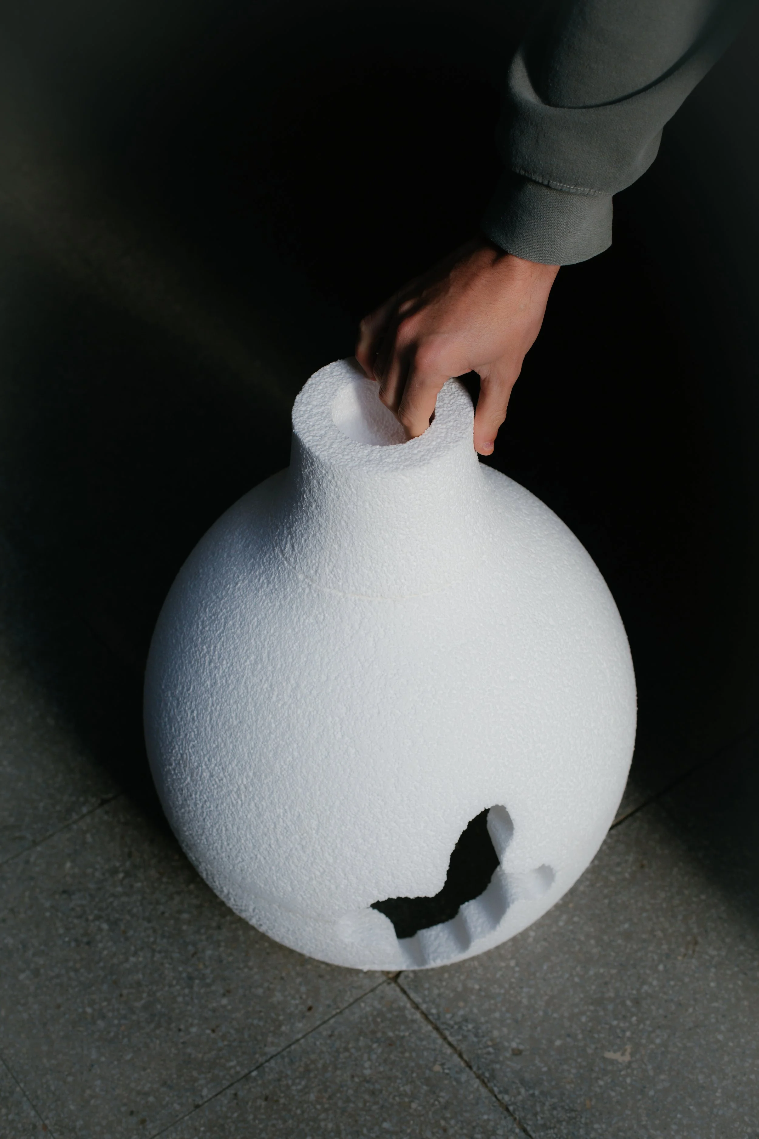 Esfera de espuma de poliestireno que tiene la forma de una calavera, con detalles en la superficie y partes rotas en la base.