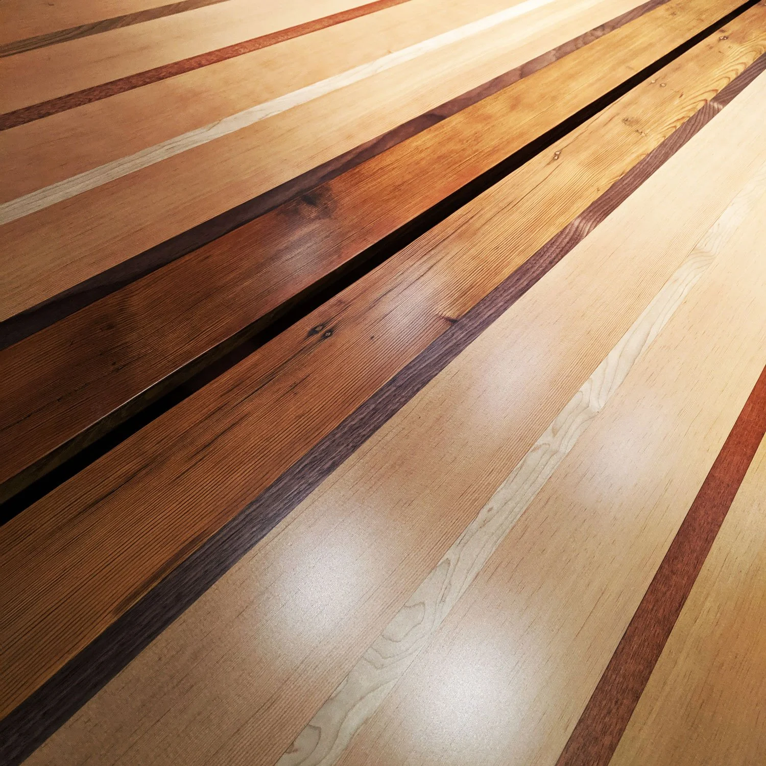 Close-up view of a wood tabletop with varying shades and grains arranged in parallel and a gap down the center.