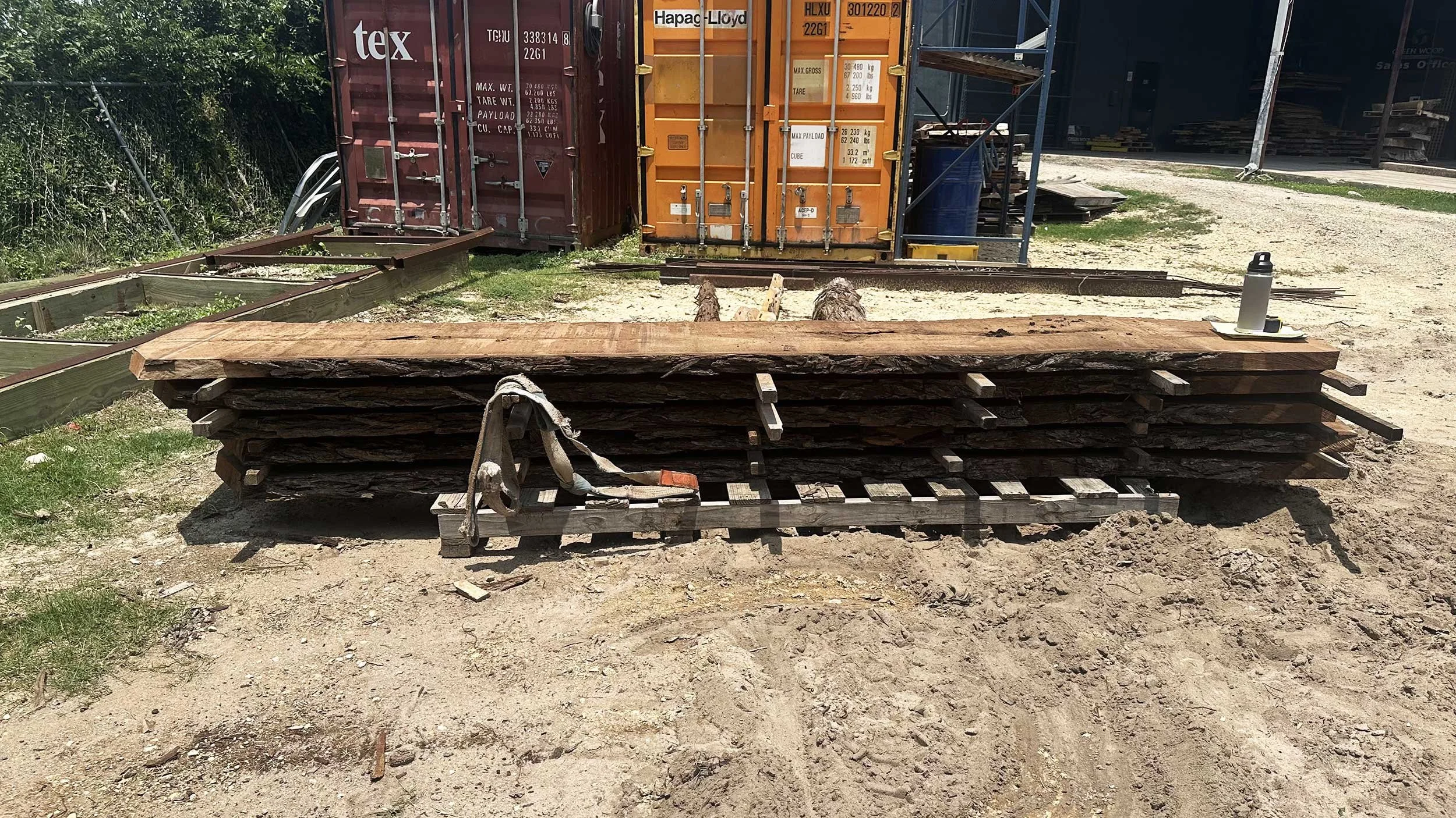 Stacked wooden slabs on a pallet outdoors.