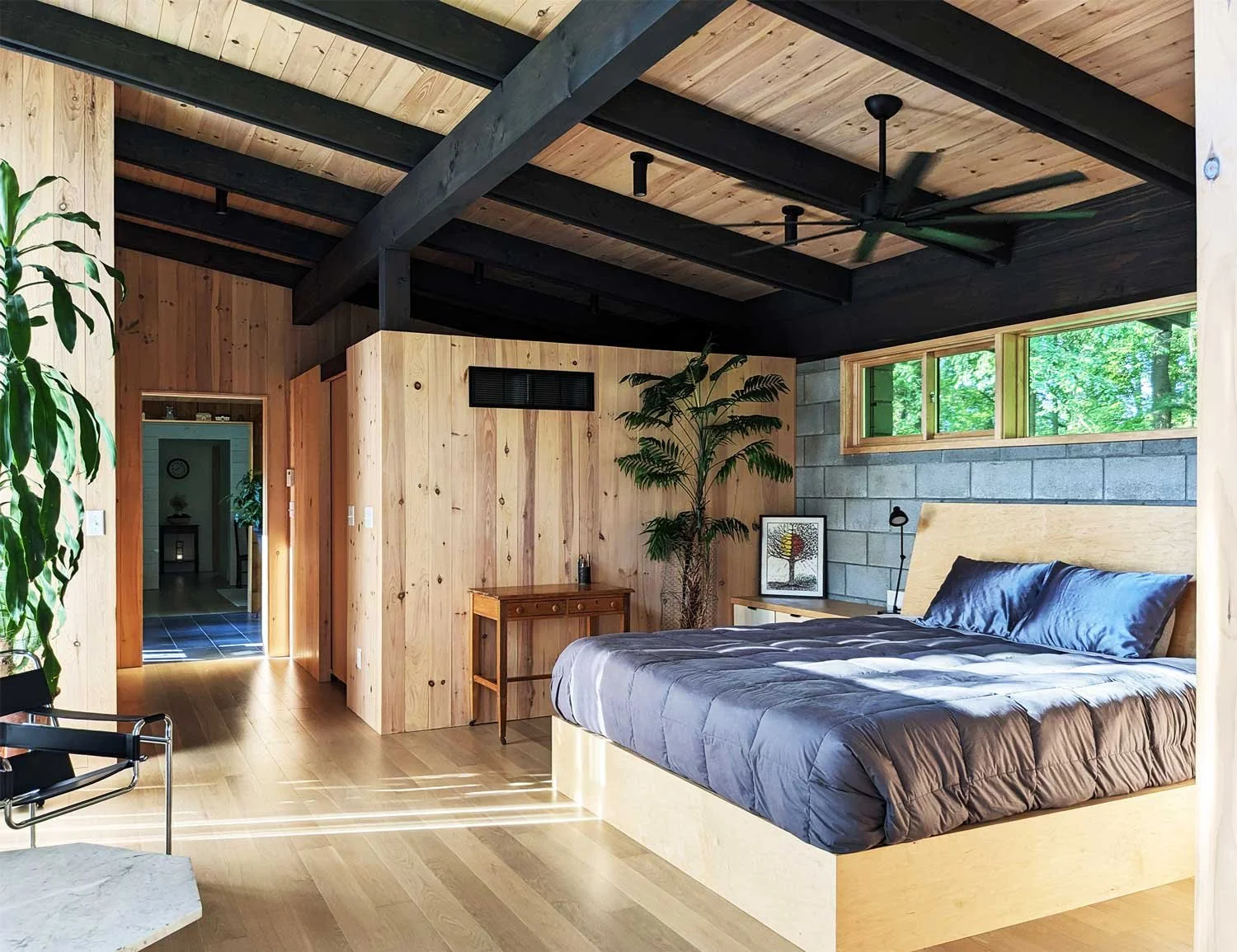 Modern bedroom with wood and concrete walls, large built-in bed, and large clerestory window.
