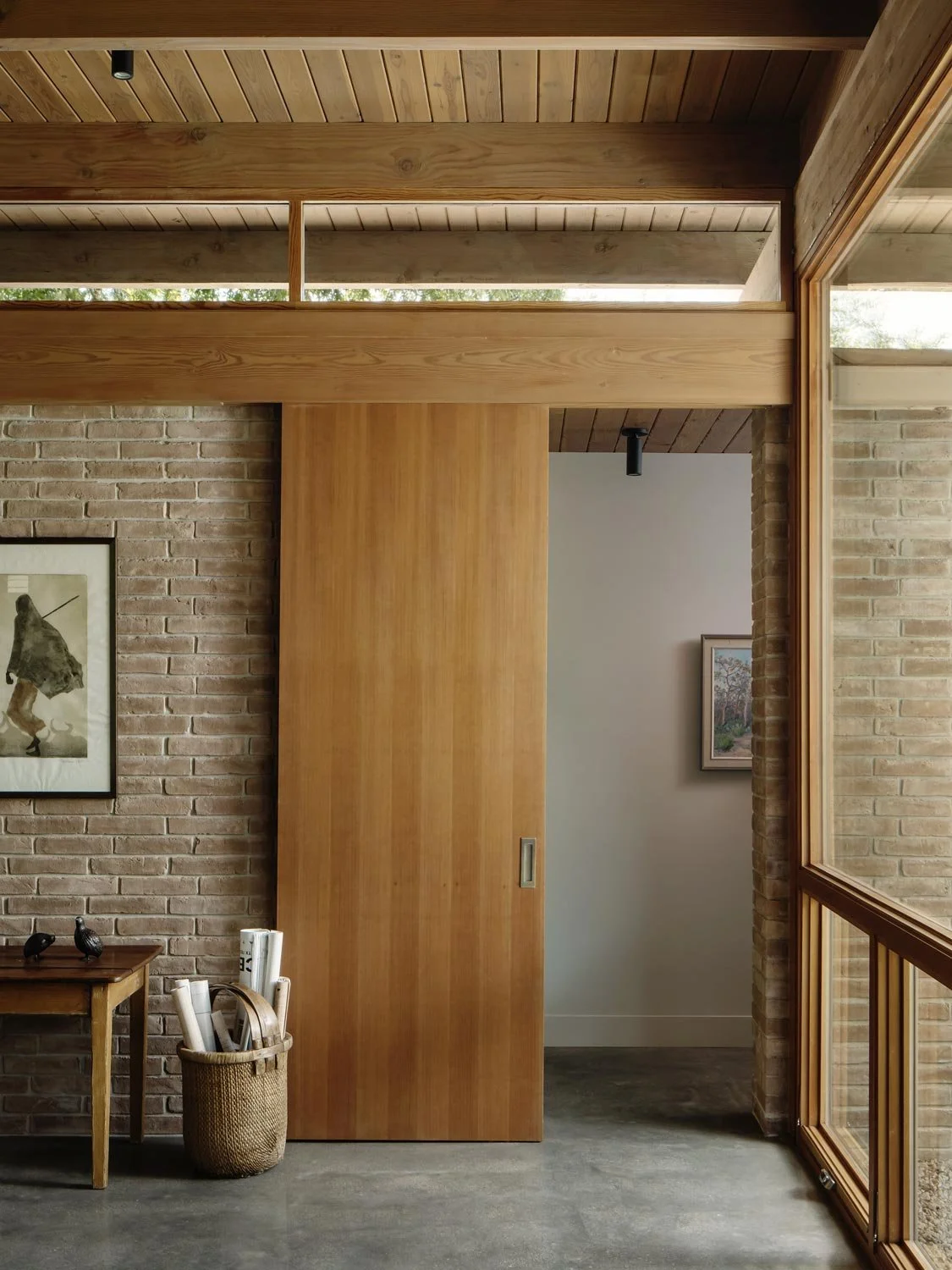 Interior view of a room with a brick wall, wooden barn door, and large glass windows.
