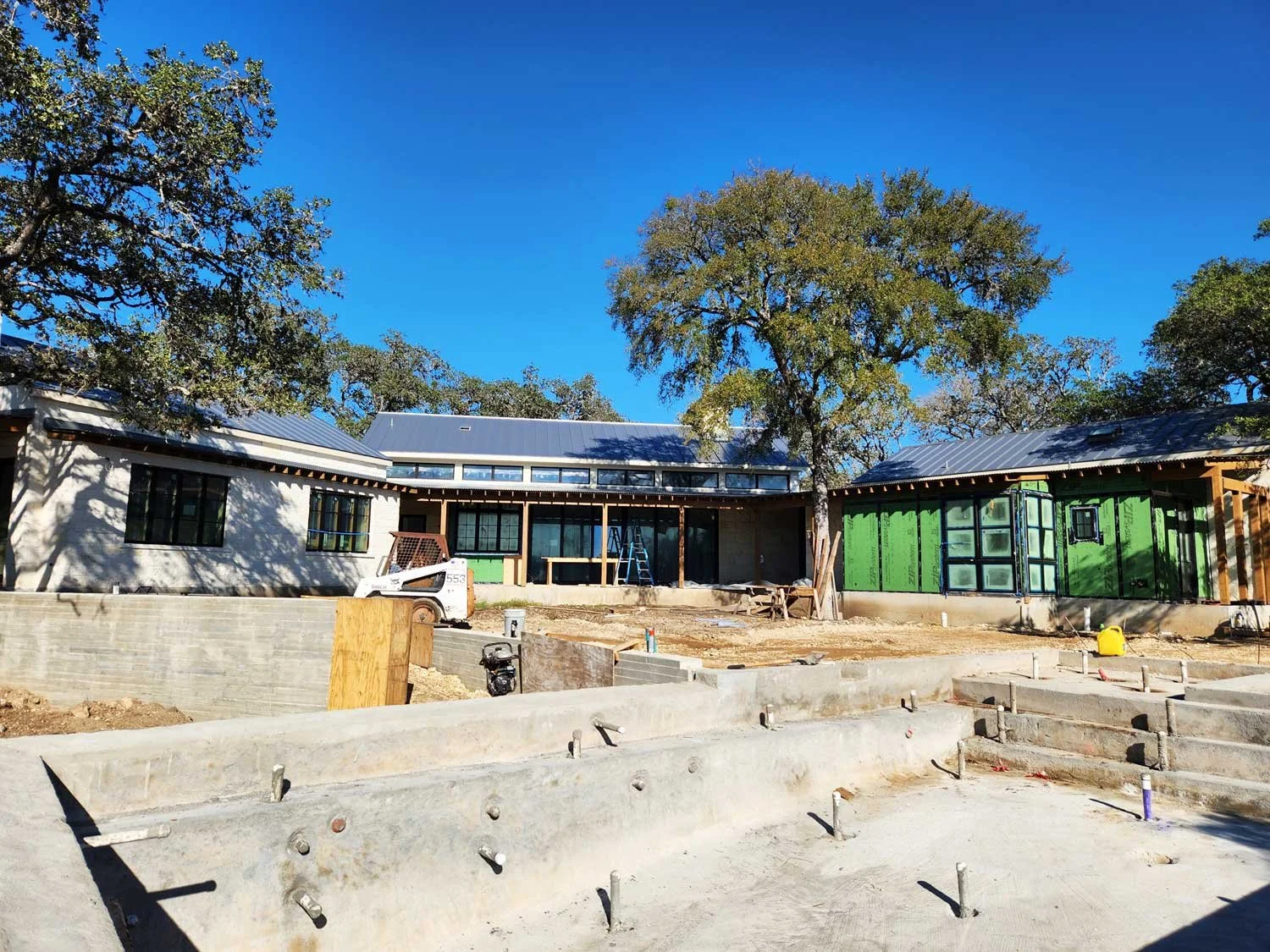 House under construction with large swimming pool in the foreground.