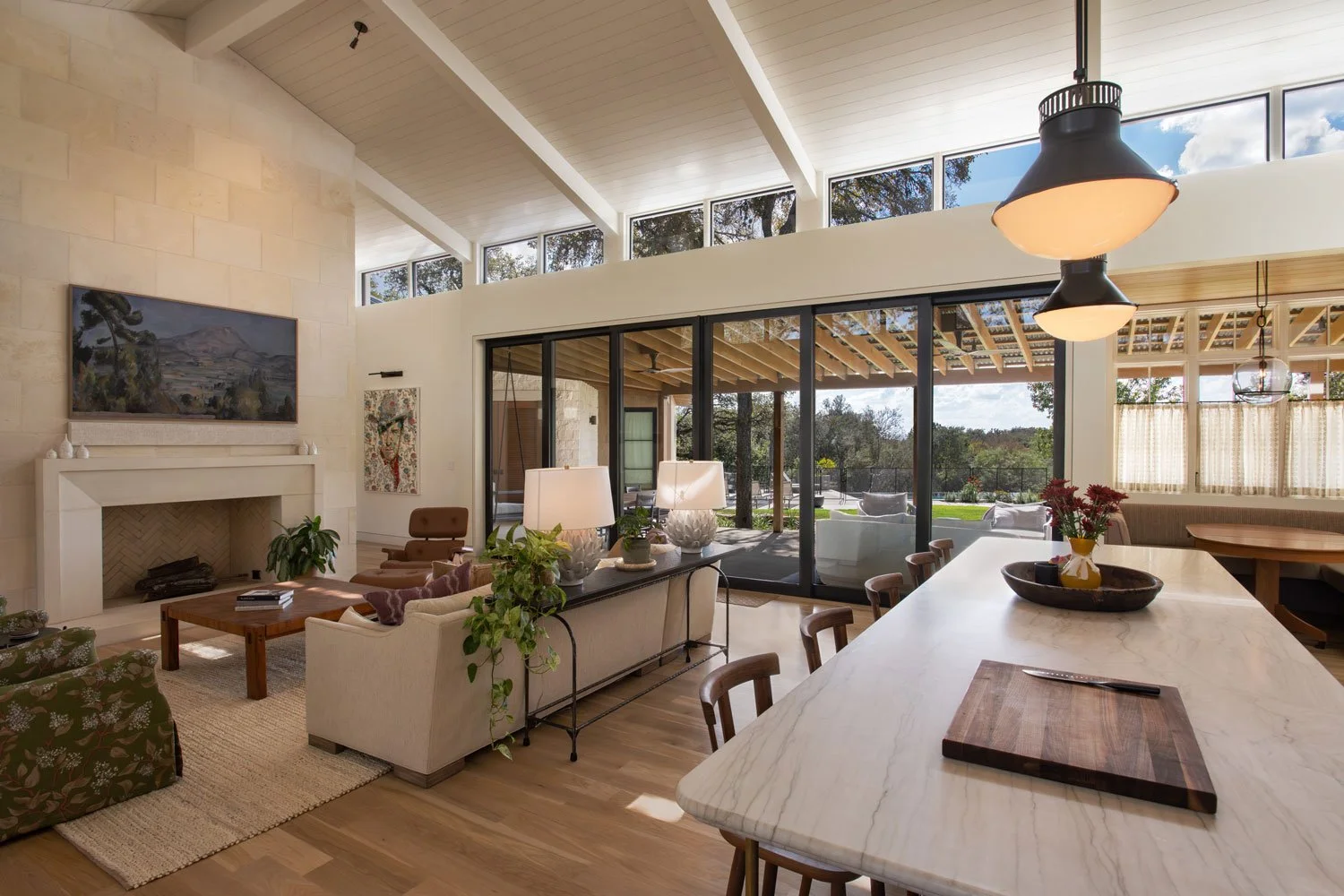 Bright living room and dining area with large sliding glass doors opening to an outdoor patio and green lawn.