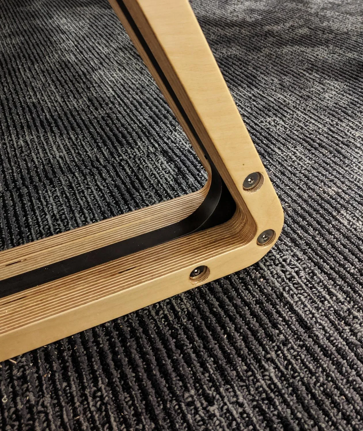 Close-up of a custom table leg made of plywood and blackened steel.