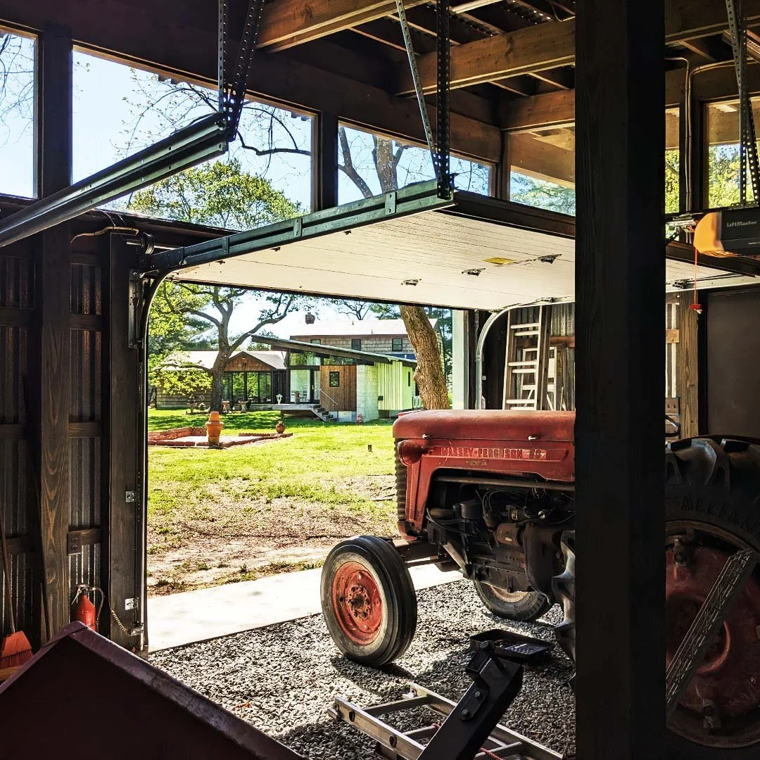 View inside a shed with the door open, showing a red tractor parked inside.
