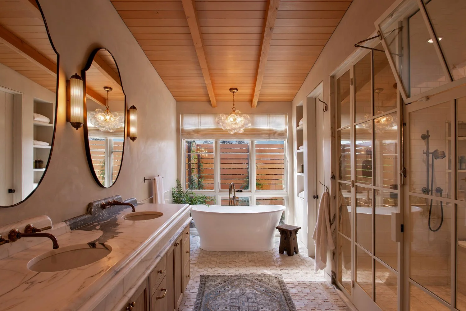 A bathroom with dual sinks, freestanding bathtub, walk-in shower with glass doors, and wooden ceiling.
