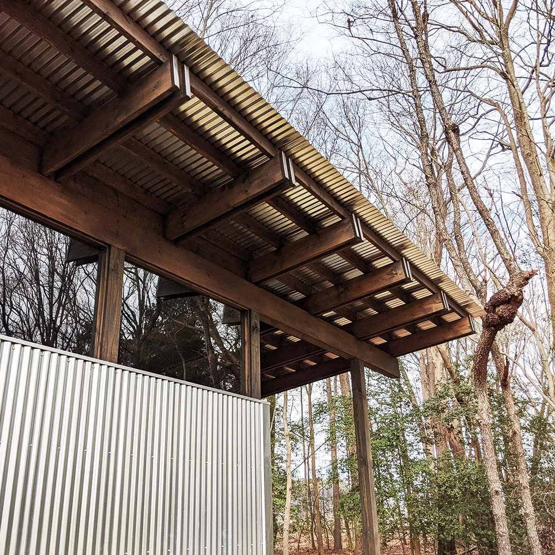 Underside of a modern shed roof overhang with a metal roof over exposed wood framing.