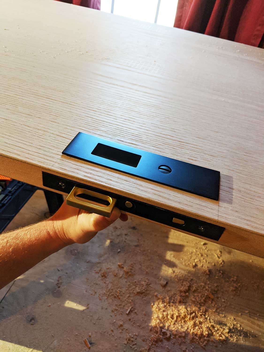 Man installing black pocket door hardware on a solid wood door.