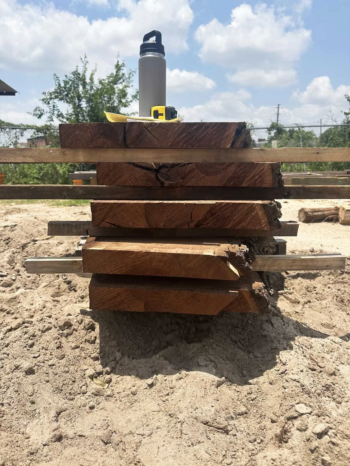 Stacked black walnut slabs outdoors.