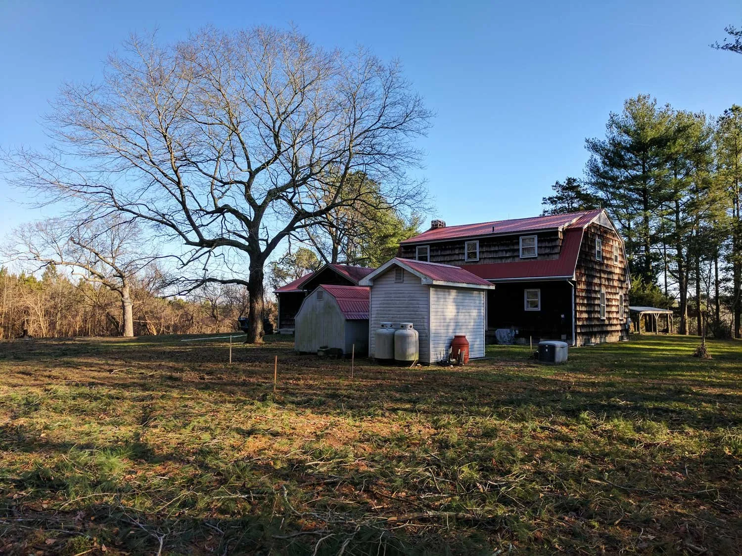 A rustic house with weathered wooden siding and a red metal roof.