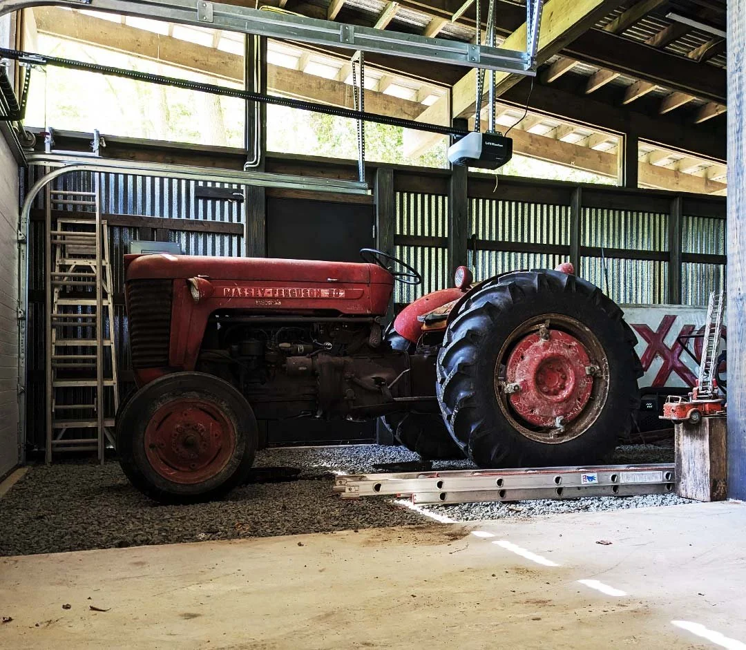 A vintage red Massey Ferguson tractor parked inside a shed.