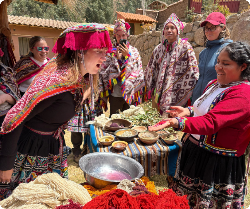 Group of women in traditional Andean clothing at a market stall, selling and buying handmade textiles and crafts in a rural village setting.