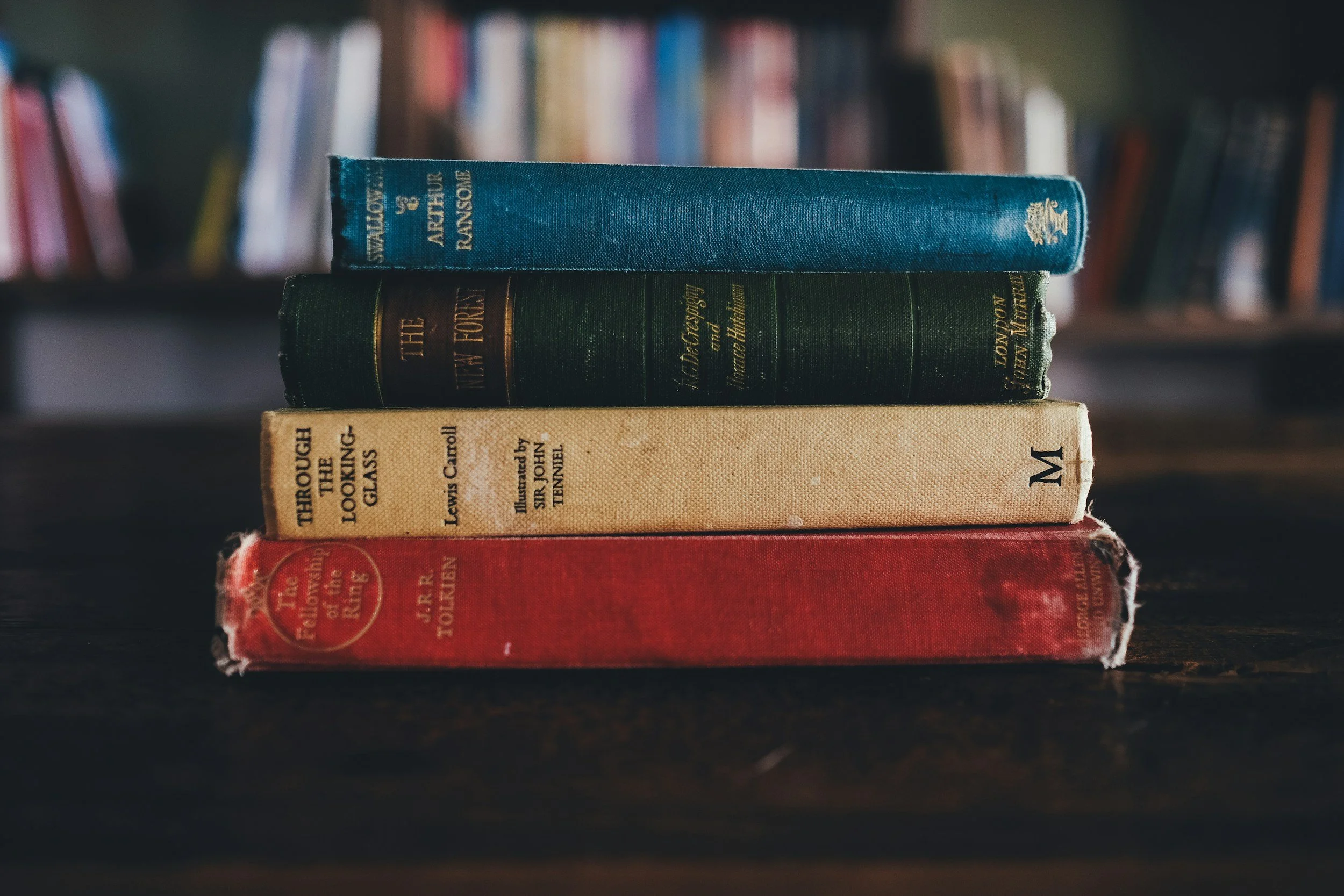 A stack of hardcover books as if on a nightstand or bookshelf that can inspire a reader to look at them and think about the adventures each book would take them on.