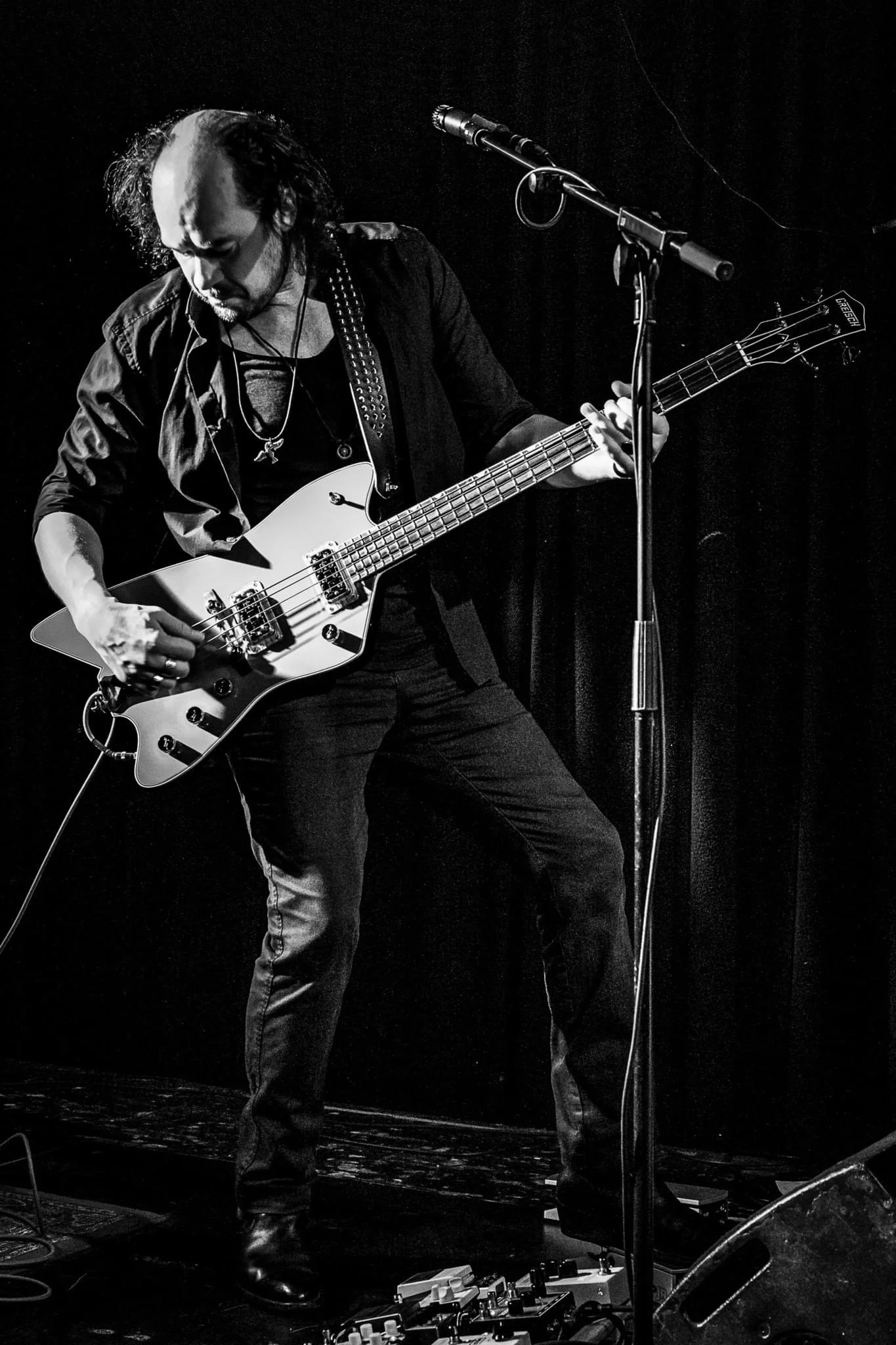 A man playing an electric guitar on stage, black and white photo.