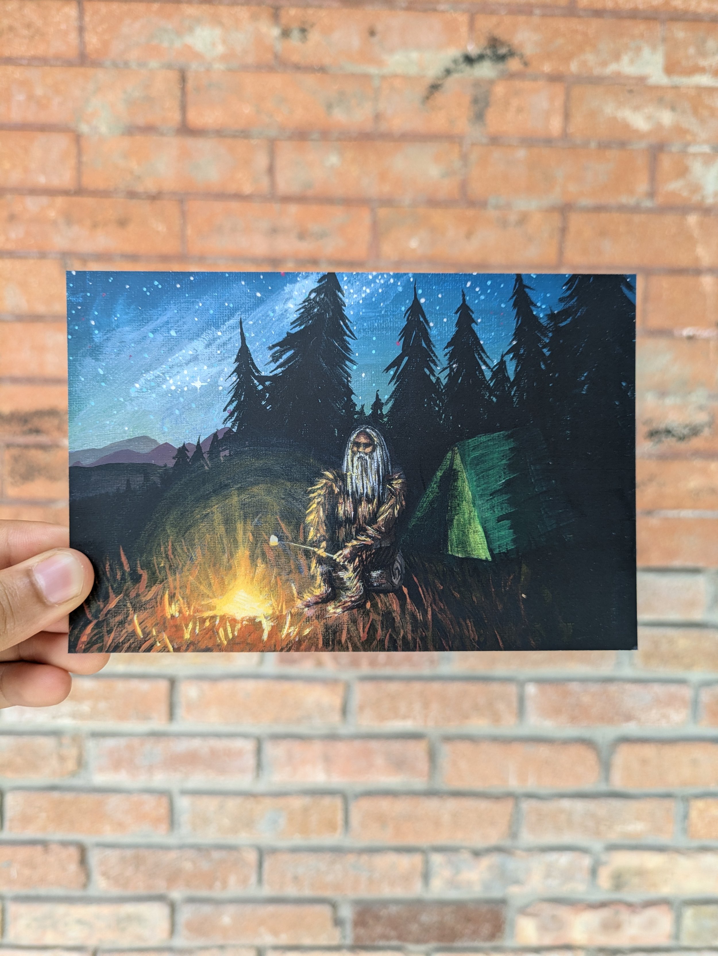 An illustrated scene of a person sitting by a campfire in a forest with a starry sky overhead and mountains in the background, next to a green tent.