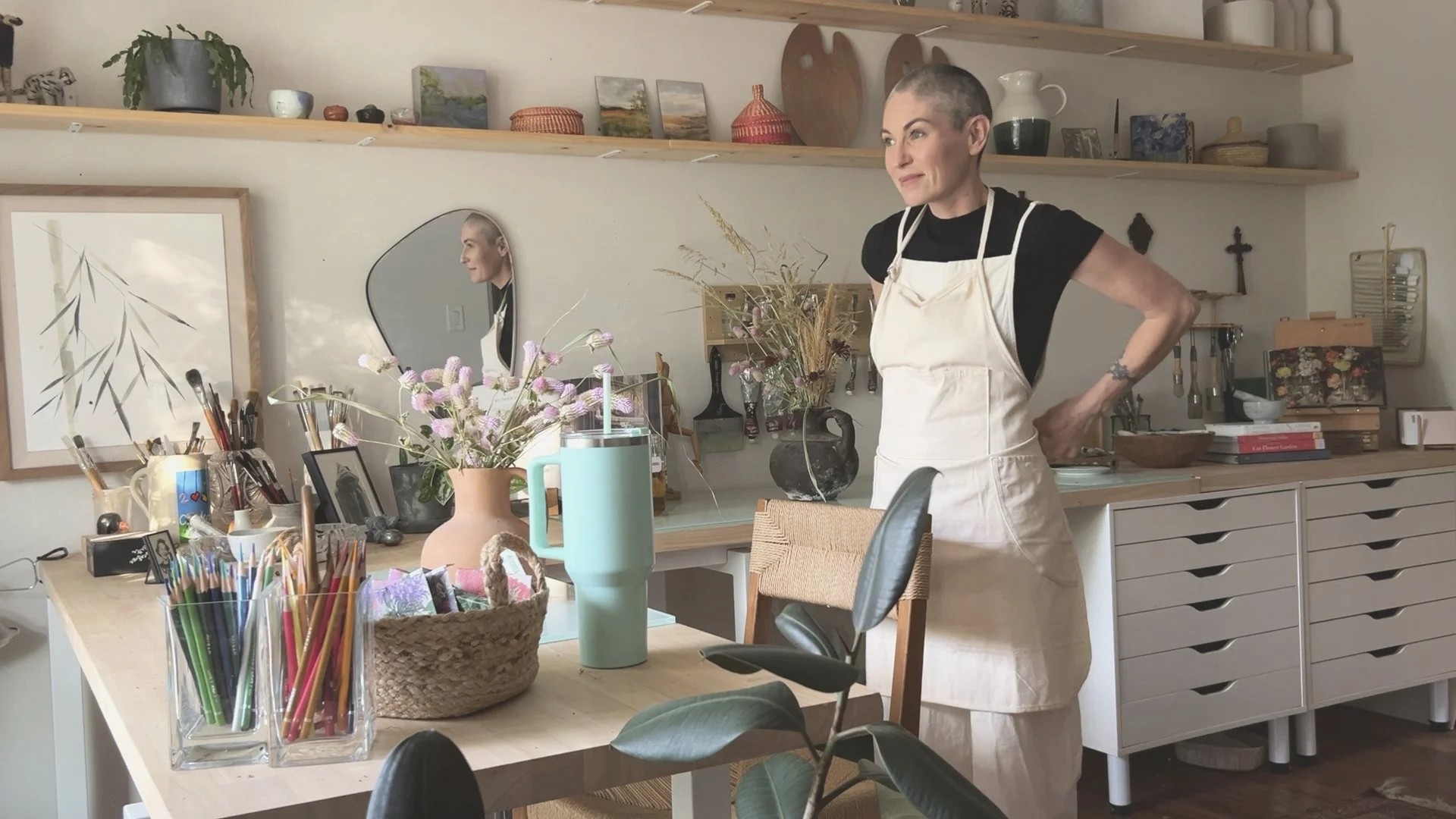 Jess Engle, working artist and creator of Artist Edit, in her studio surrounded by paintings and creative tools.