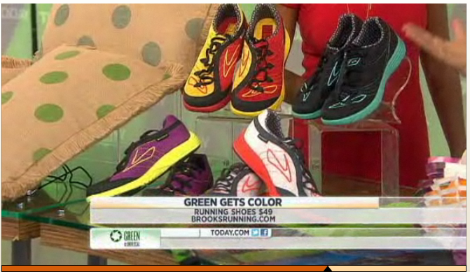 Display of colorful running shoes on a glass table with a news caption about shoes costing $49.