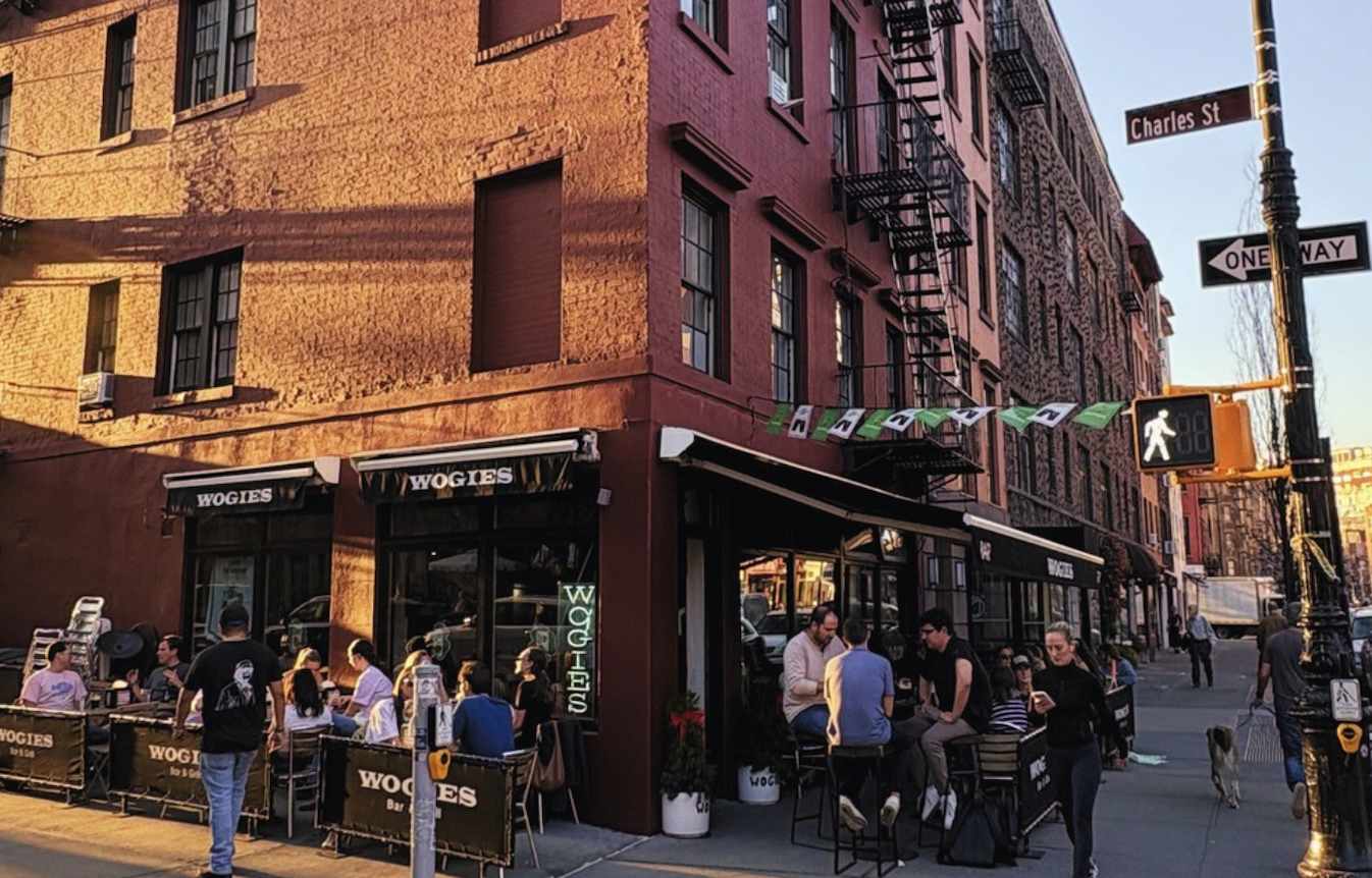 Exterior of Wogies West Village with guests dining outdoors on a New York City street corner.