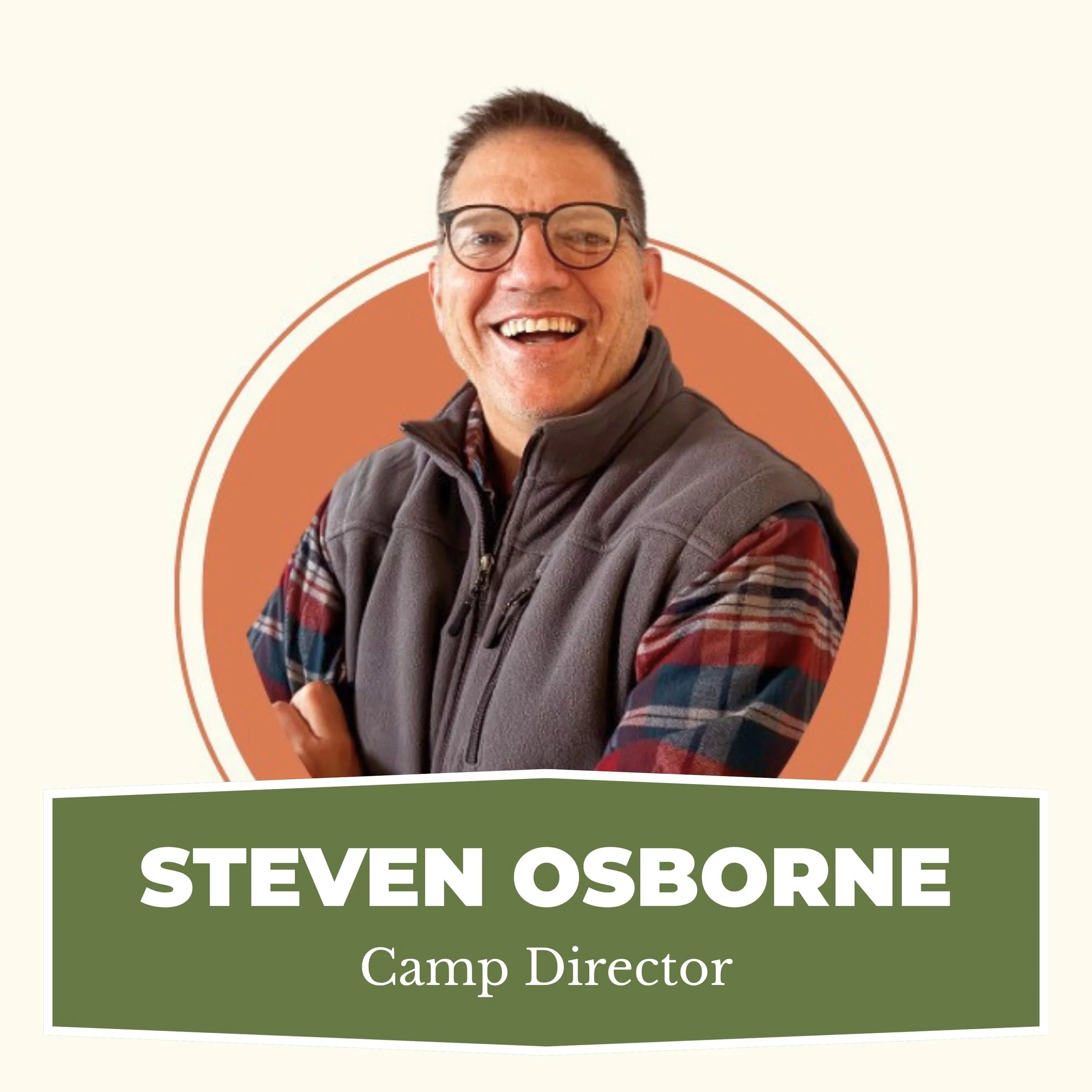 A smiling man wearing glasses, a vest, and a plaid shirt, with a camp director nameplate in front of him.