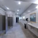 Modern kitchen with white cabinets, stainless steel refrigerator, pendant lighting, and a large window.