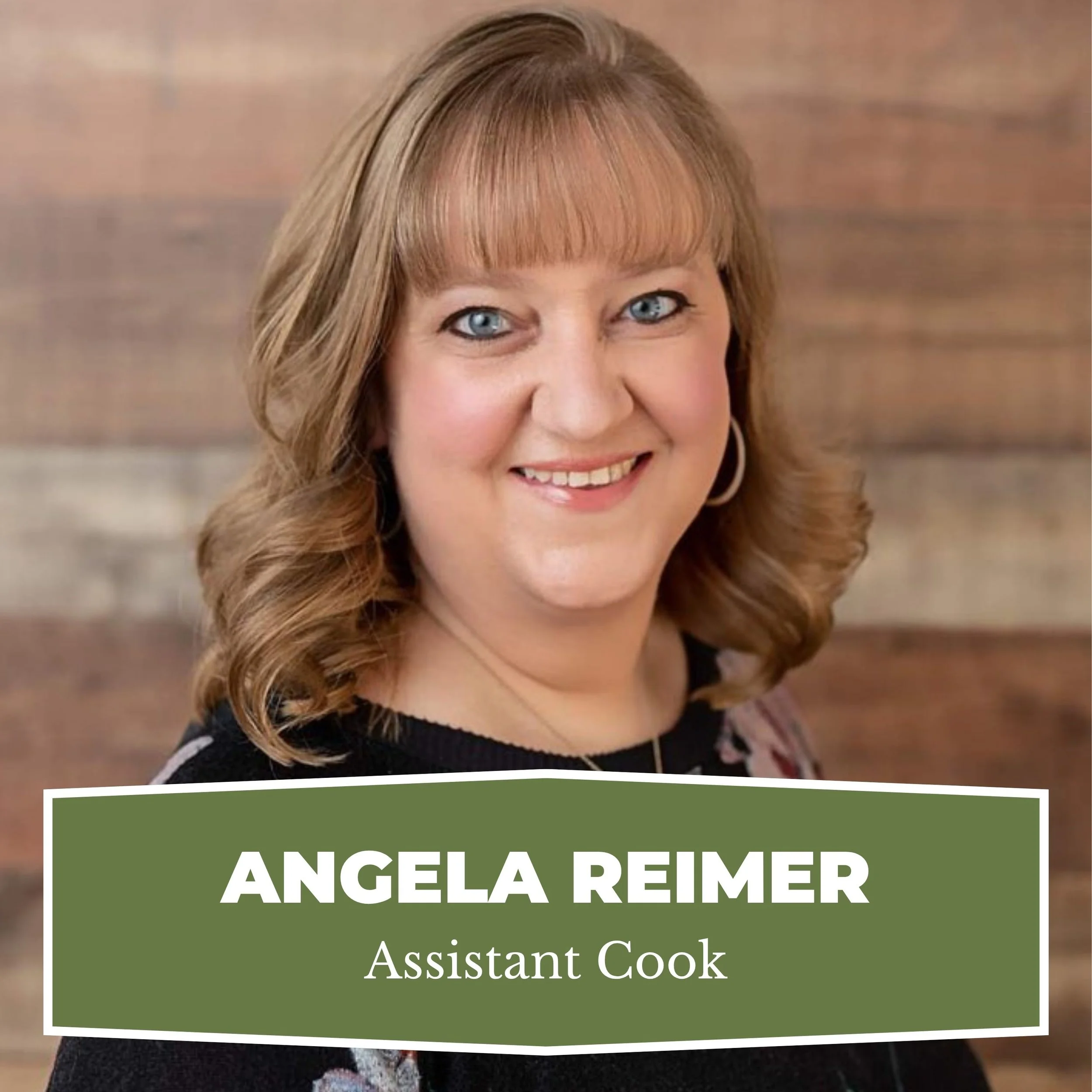 A woman with shoulder-length wavy red hair, wearing a black top and hoop earrings, smiling in front of a wooden background. The image has a green banner with white text that reads 'Angela Reimer, Assistant Cook.'