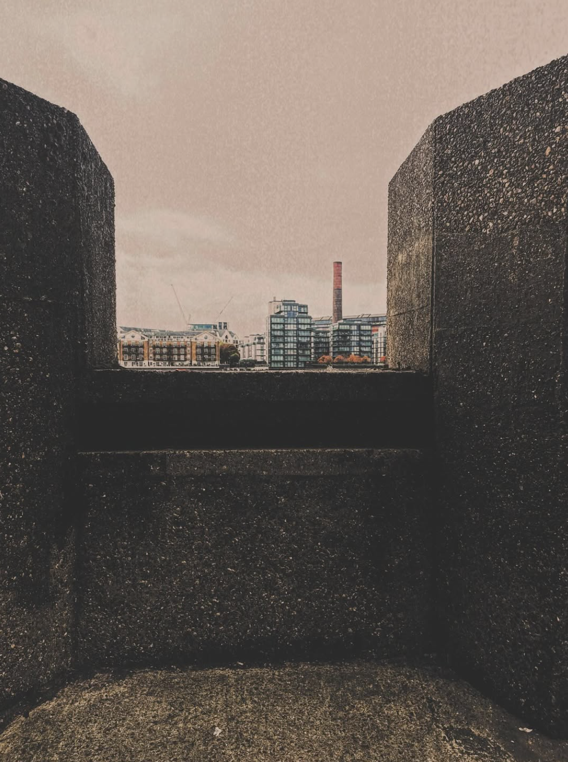 A city view seen from between two bricks on a wall.