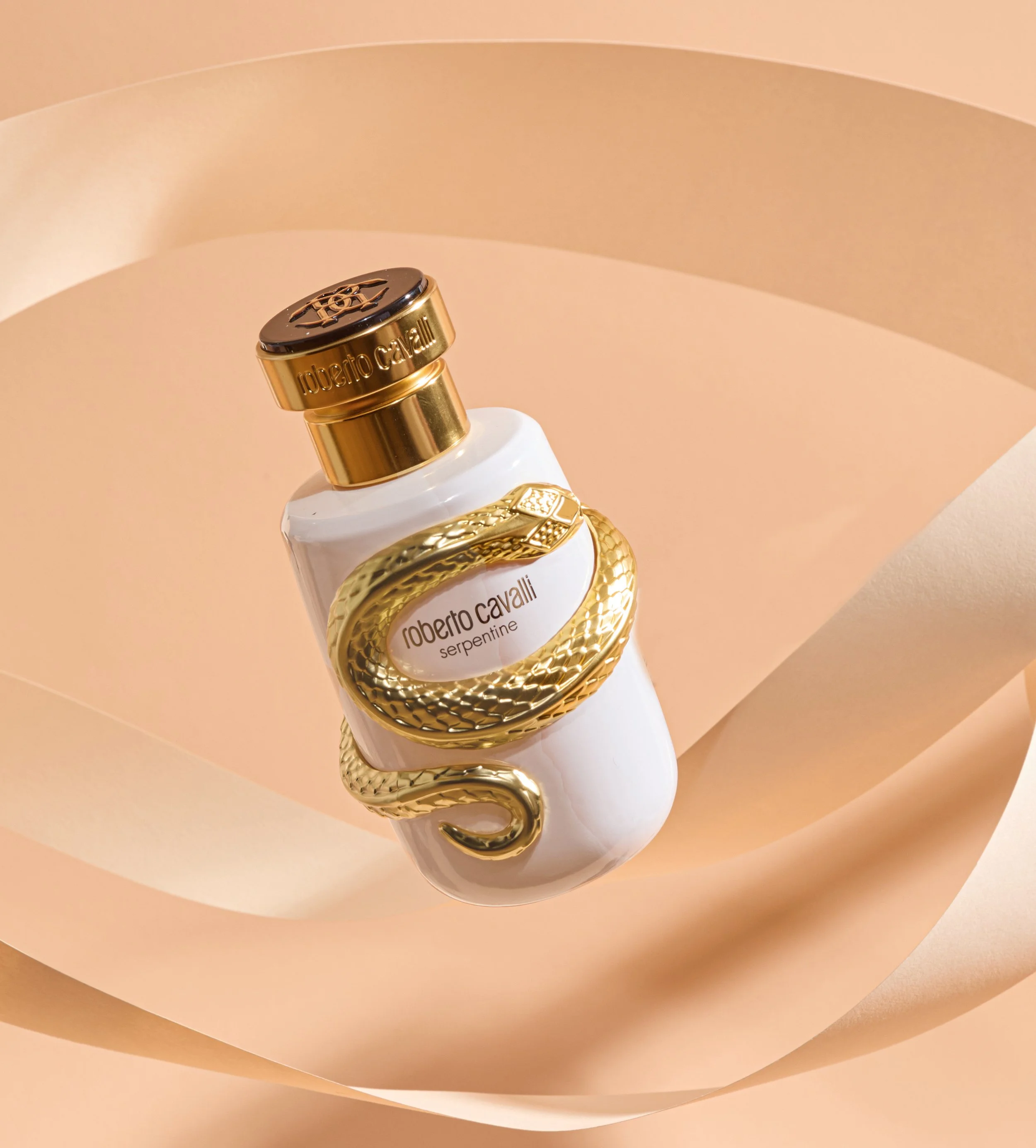 Roberto Cavalli Serpentine perfume bottle with gold snake detailing on a peach background