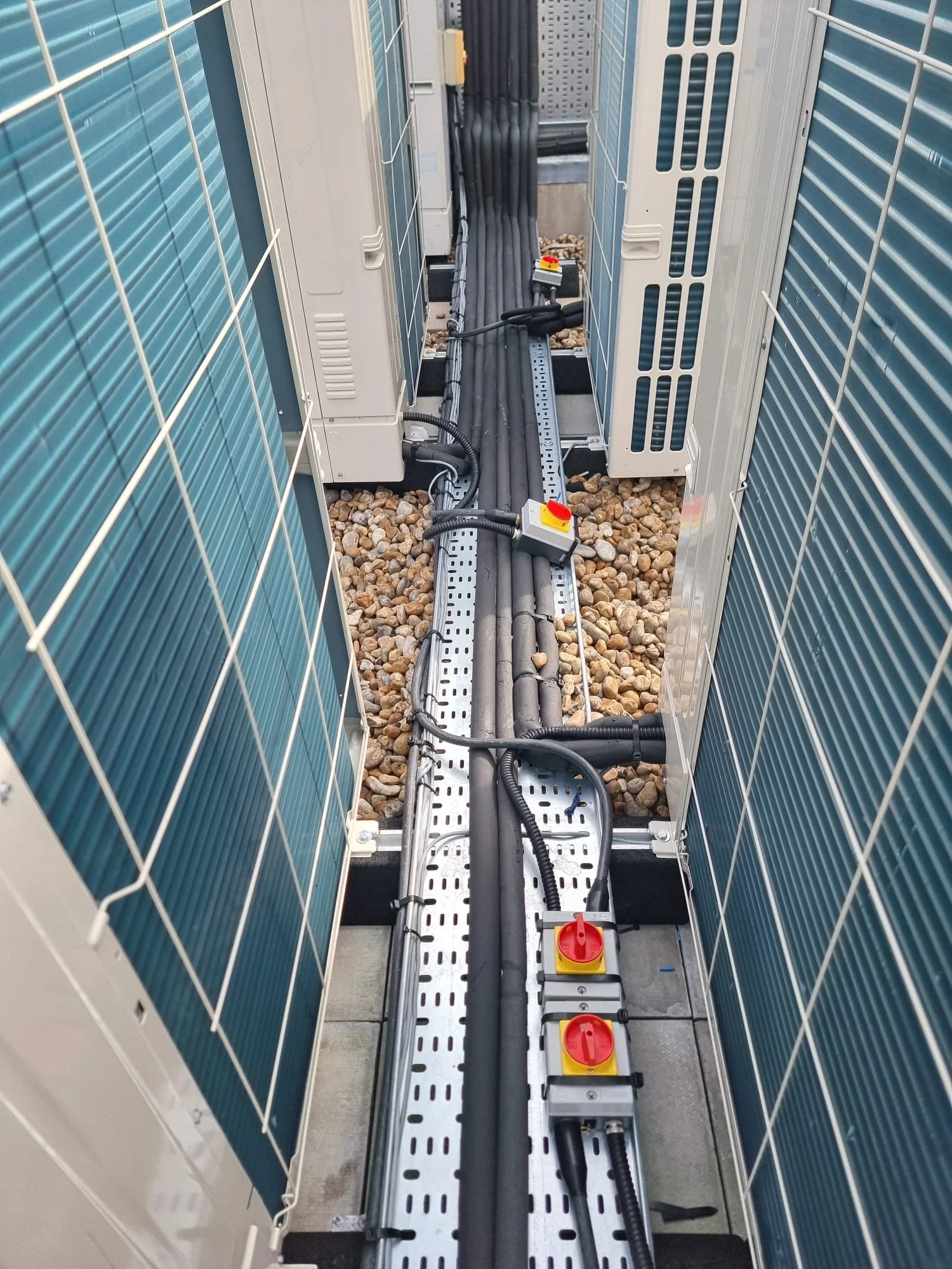 Close-up of electrical cables, connectors, and circuit breakers in an outdoor utility enclosure with solar panels on the sides.