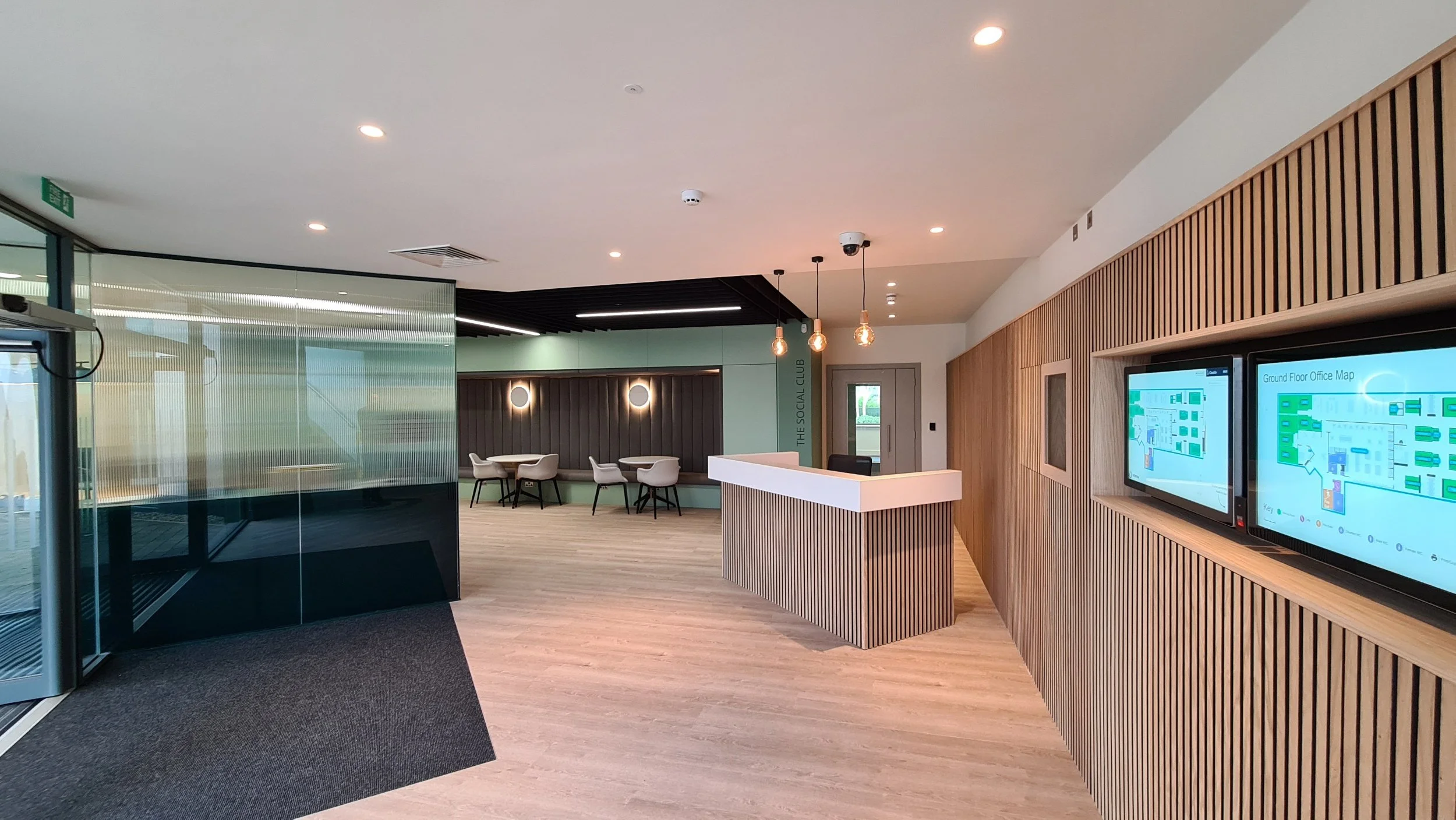 Modern lobby or reception area with seating, digital displays, and wood accents.
