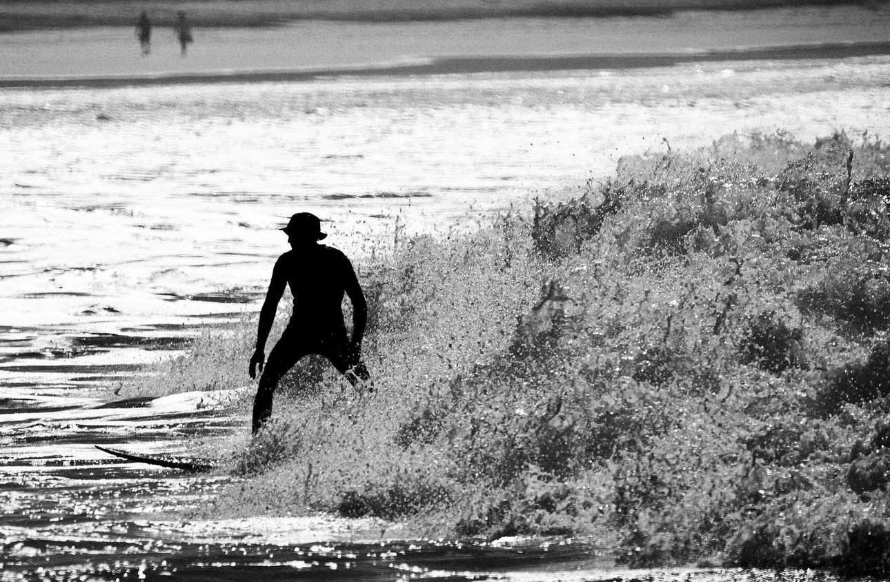 A person surfing on a wave at the beach during daytime.