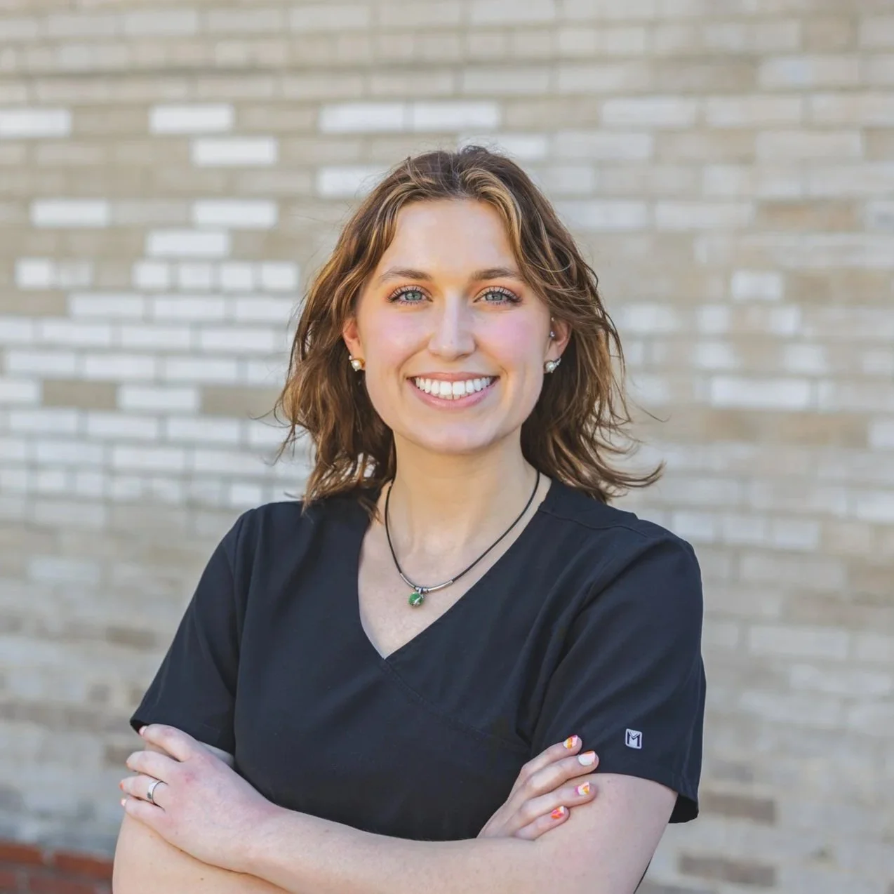 Headshot of smiling female tutor with long braids wearing a lanyard.