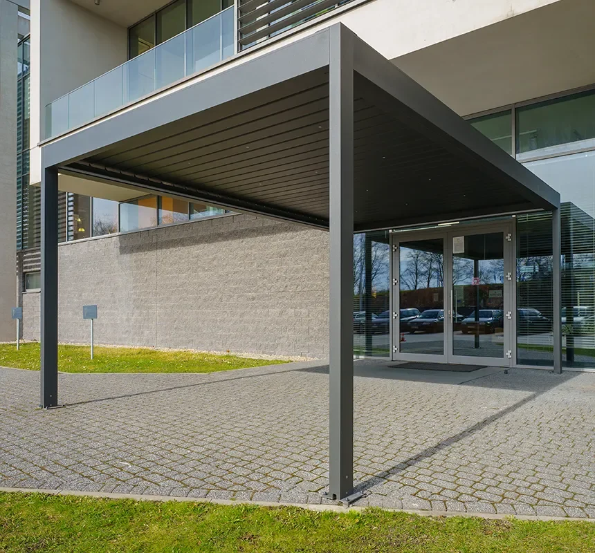 Modern commercial building entrance with a large covered canopy, glass doors, and paved walkway