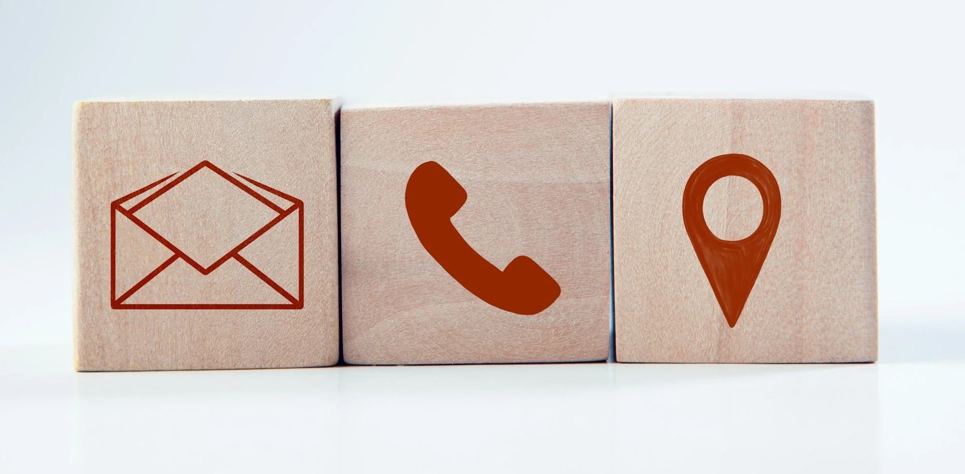 Three wooden blocks with symbols: an envelope, a phone, and a location pin.