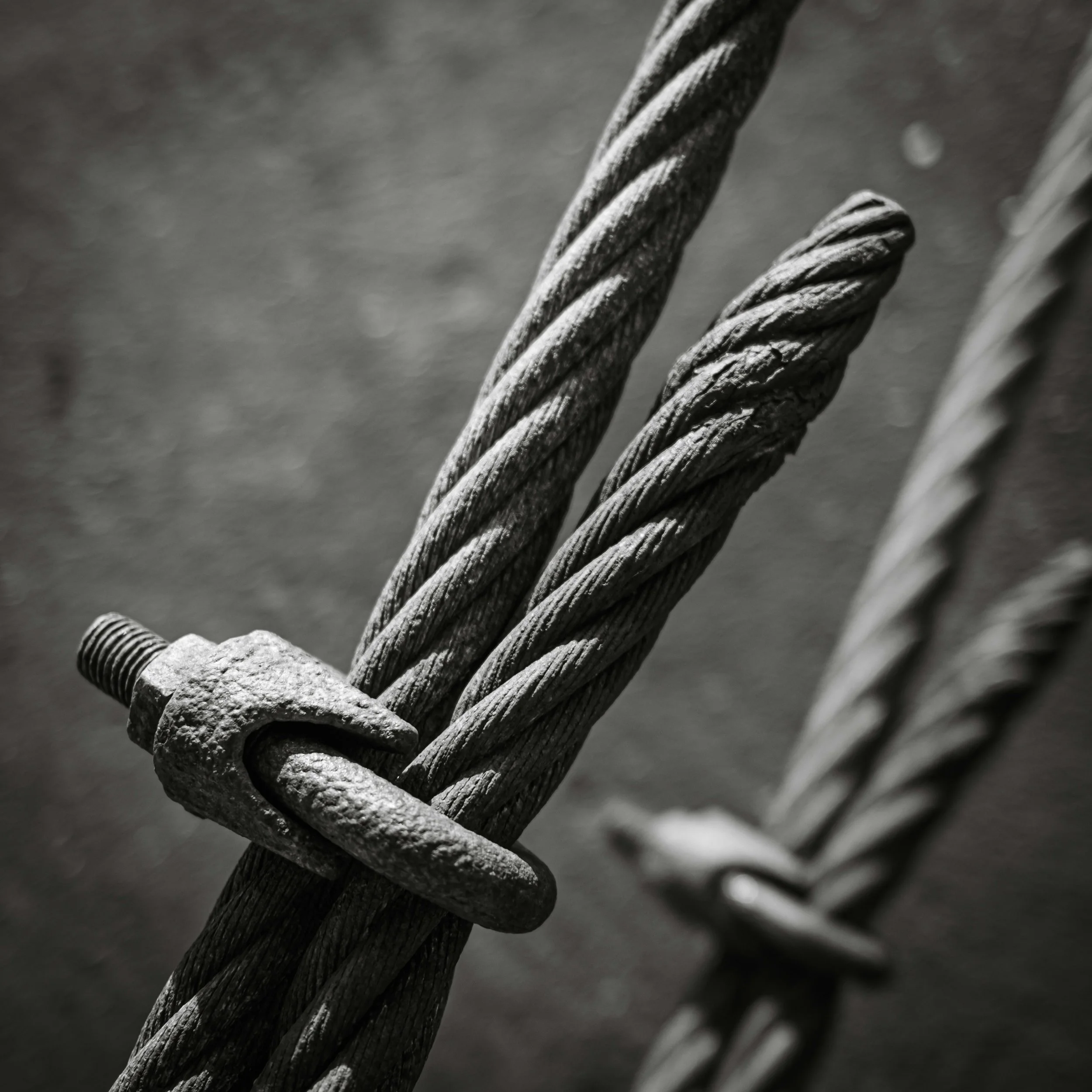 Close-up of metal wire ropes twisted together, showing their rough textured surface.