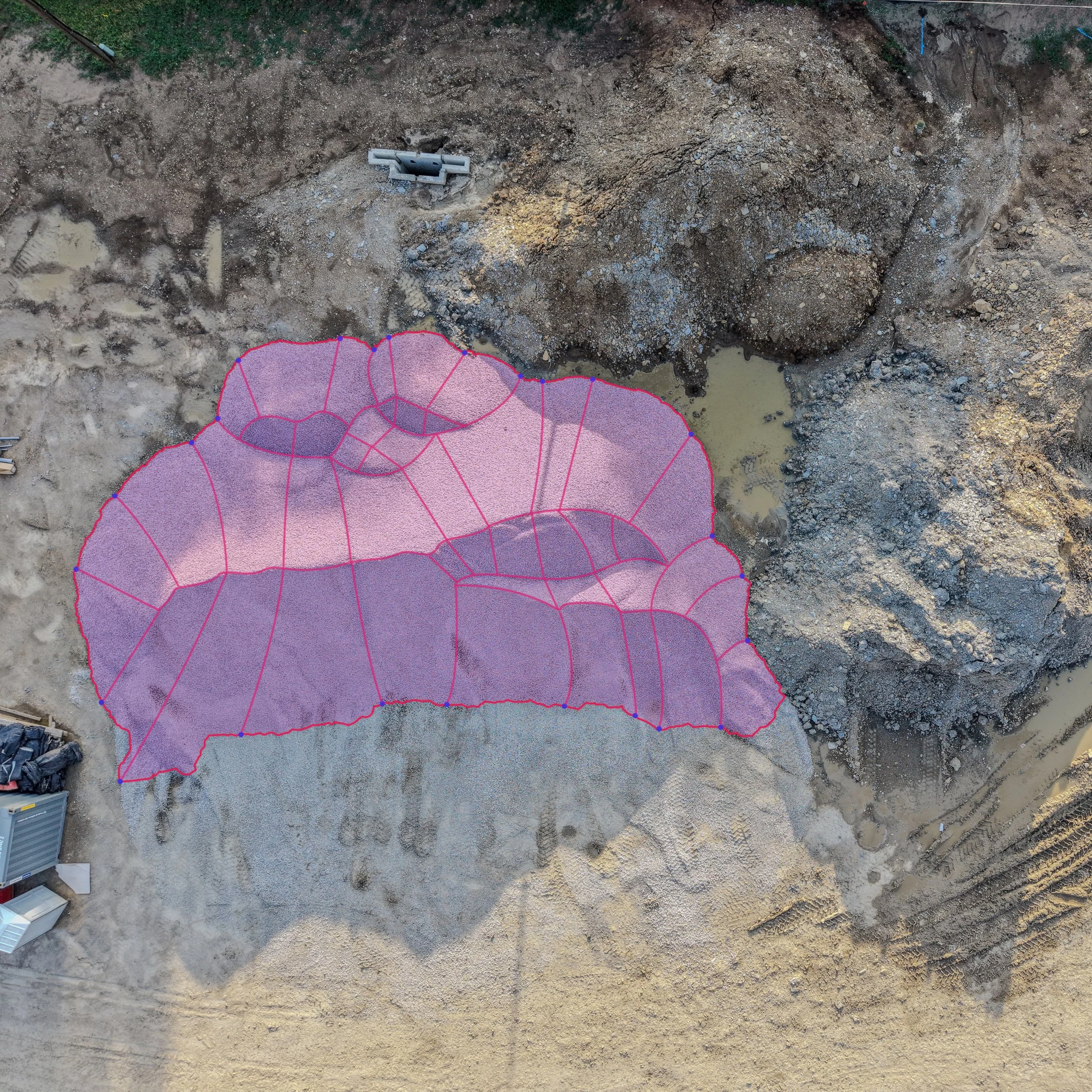 Aerial view of a construction site with a purple geo-fencing outline, erected around a large area of excavated ground.