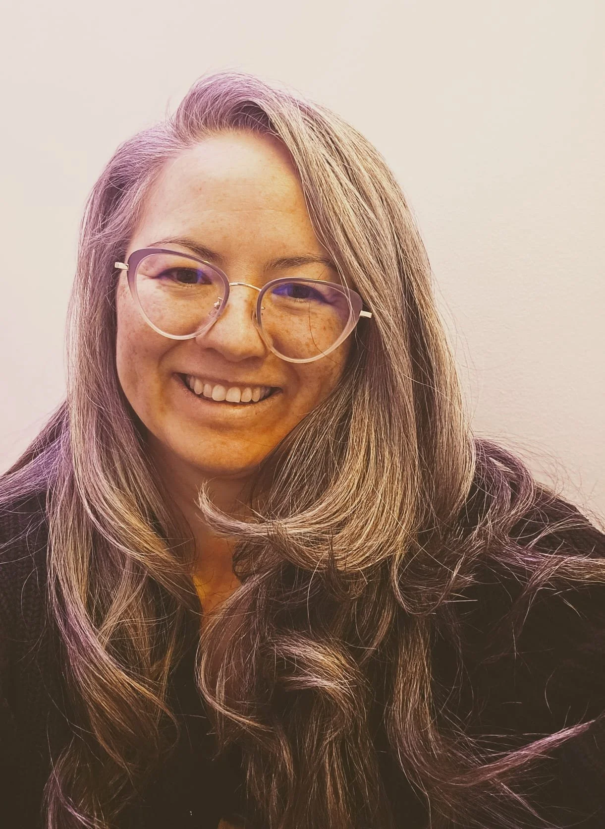 Headshot of Jessamyn, a mixed race woman with long grey hair, wearing glasses and smiling