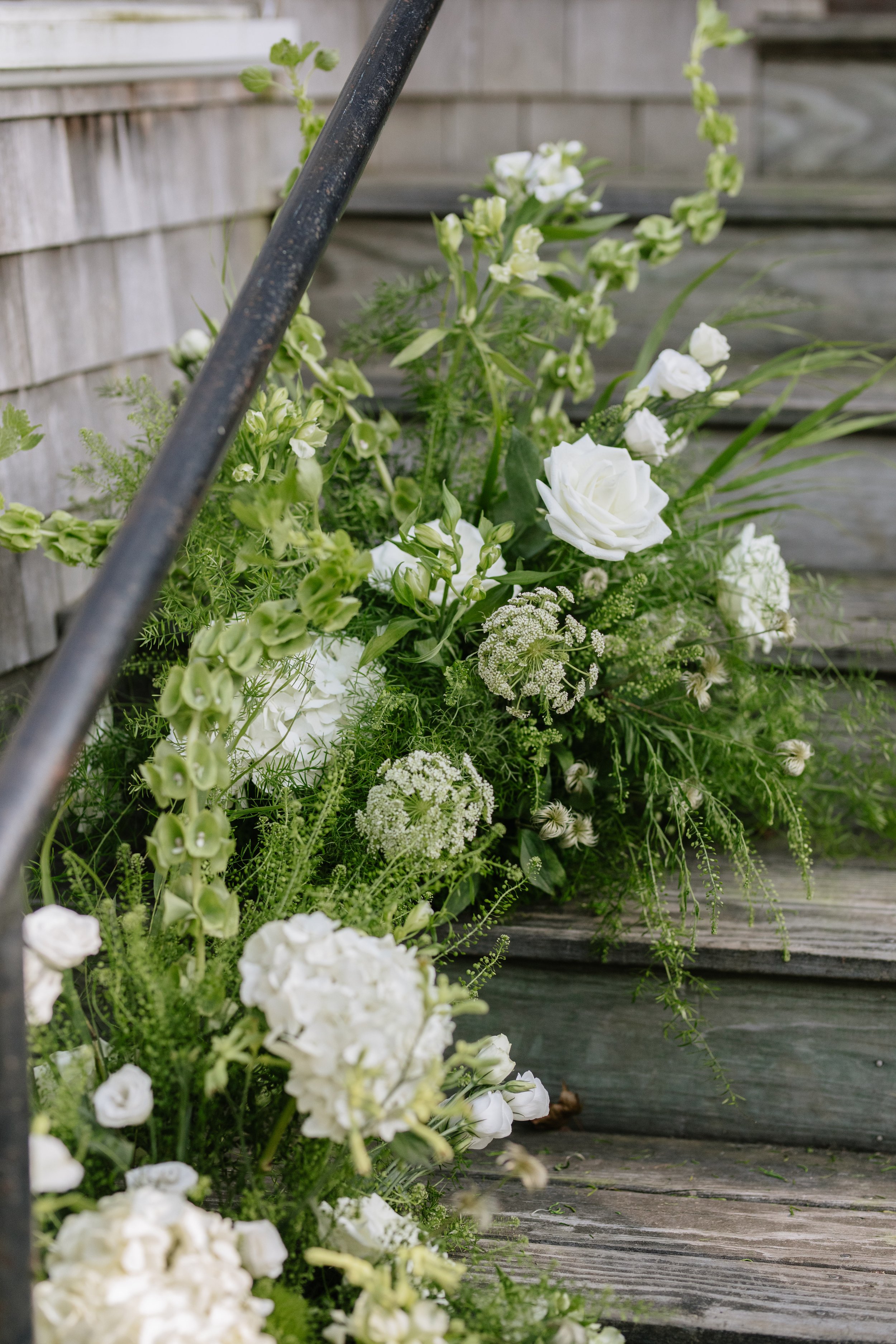 White flowers arranged on wooden steps beside a black metal railing.