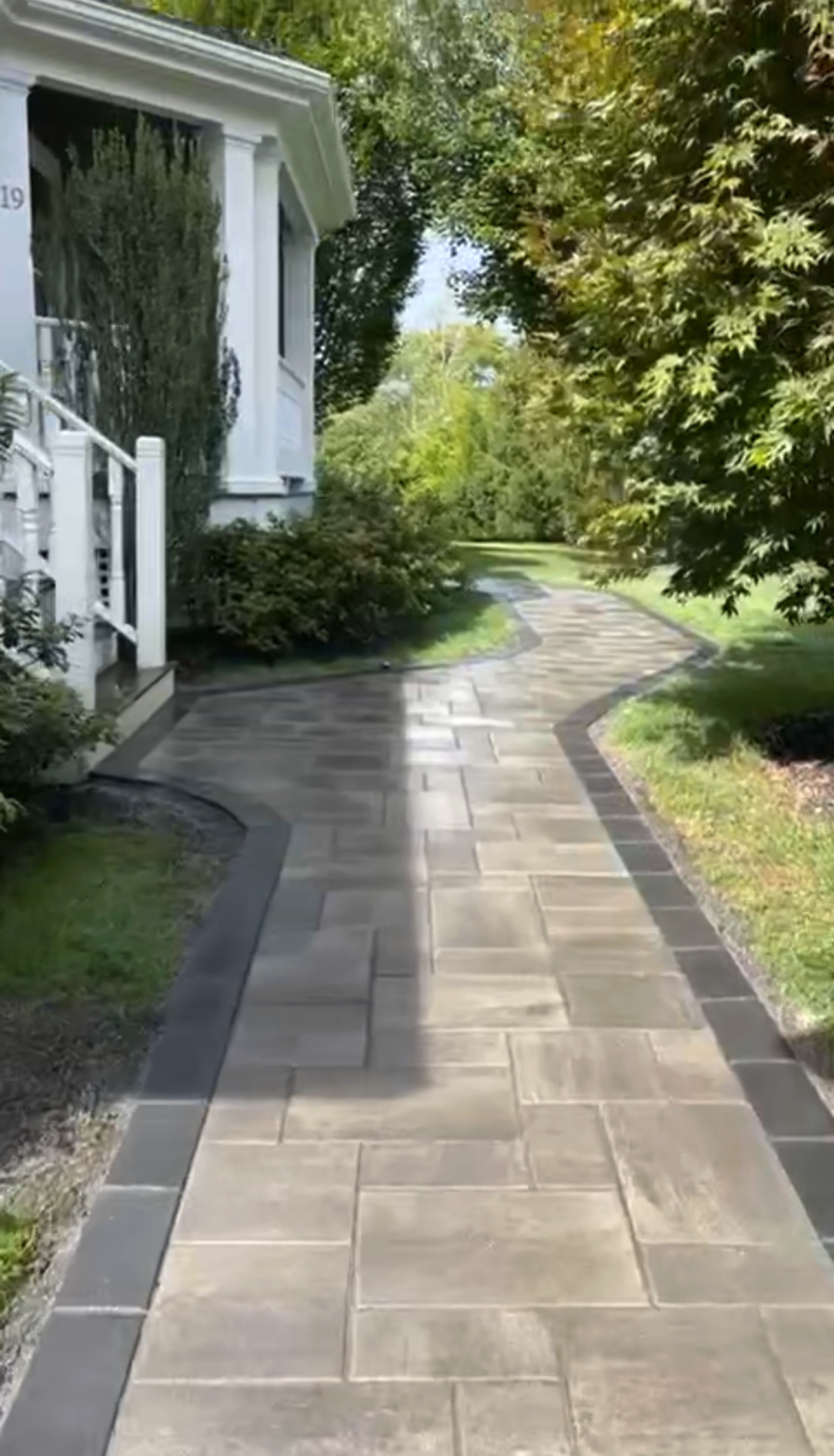Stone walkway and landscape design installation in Metrowest Boston residential yard with greenery and trees. (Weston, MA)