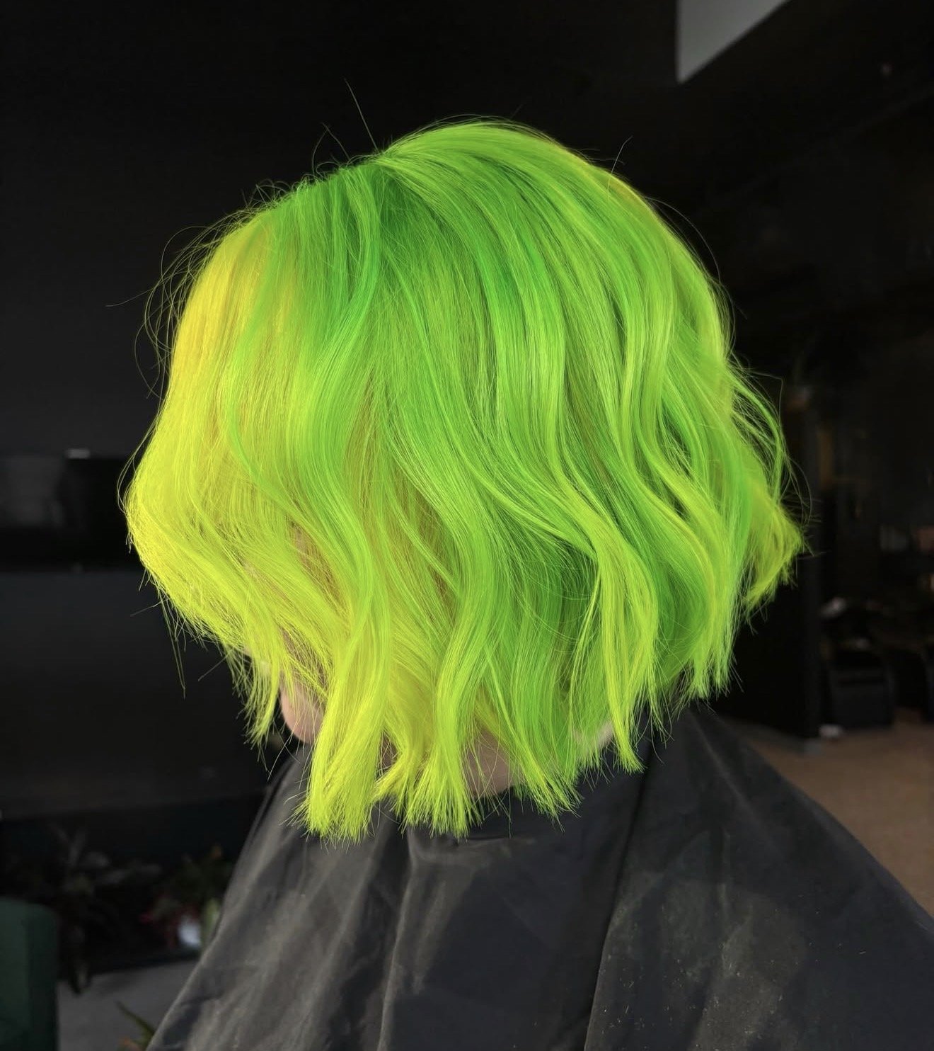 Colorful hair with shades of bright green and yellow, styled in loose wavy layers.