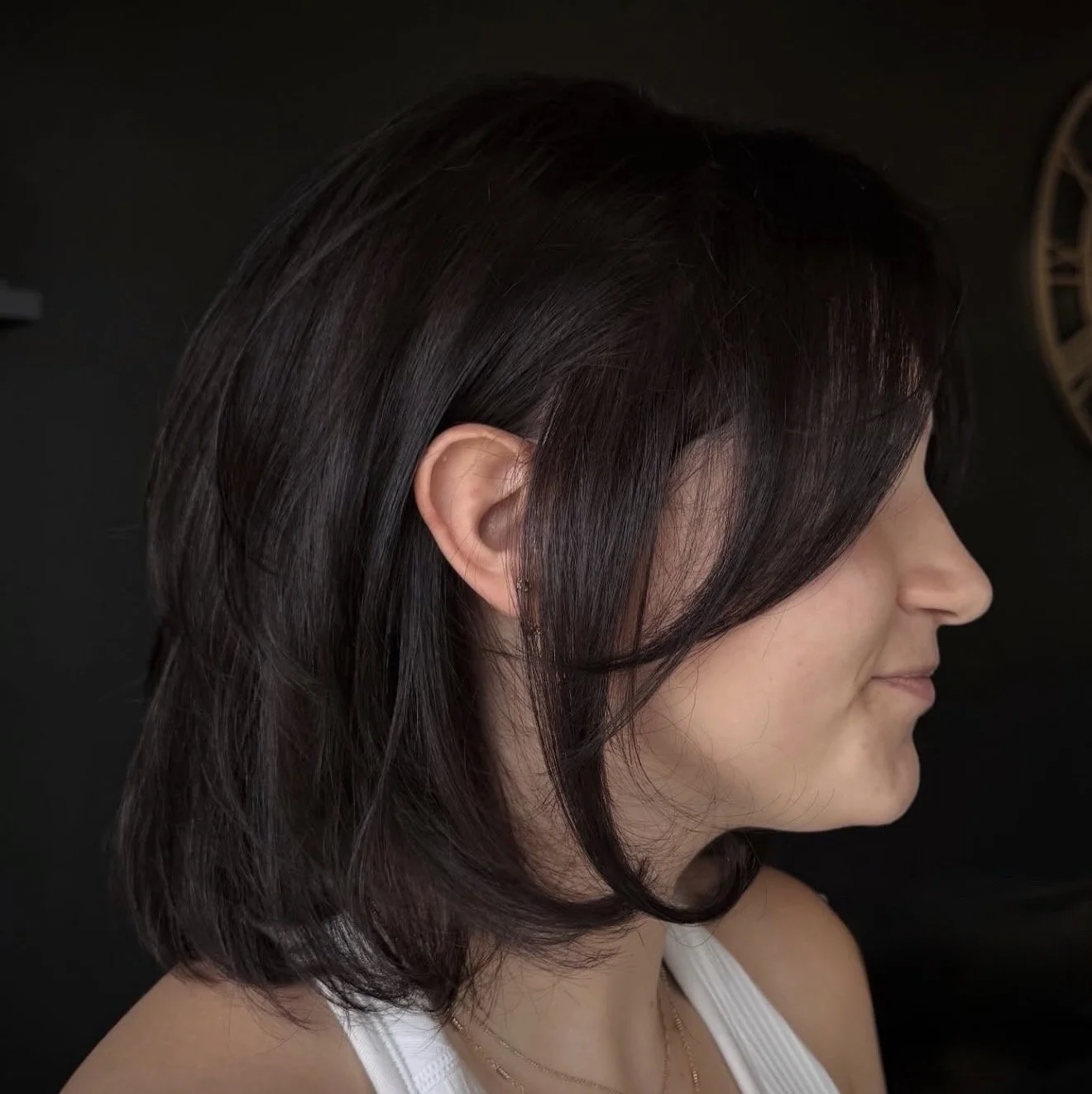 Side profile of a woman with dark brown, layered bob hairstyle.