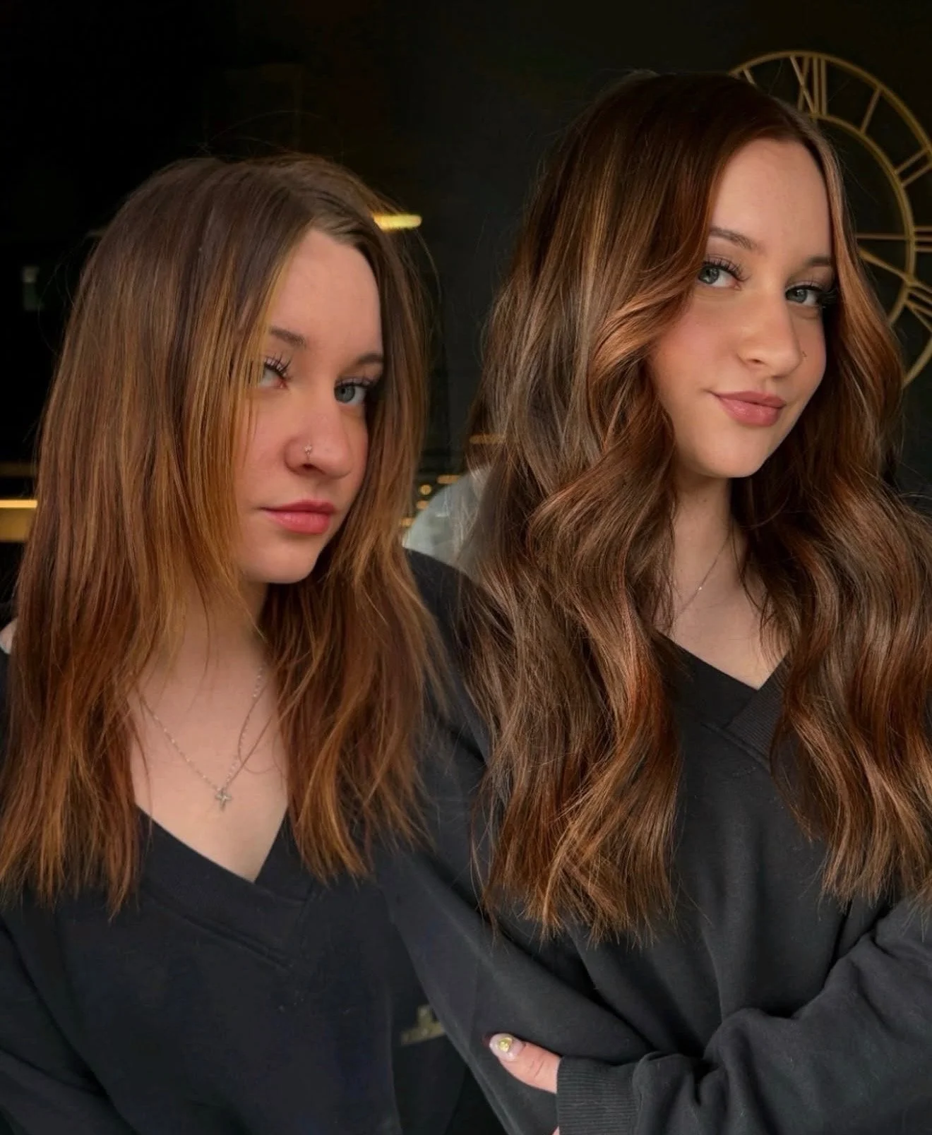 Two women with long, reddish-brown hair posing indoors, with a clock in the background.