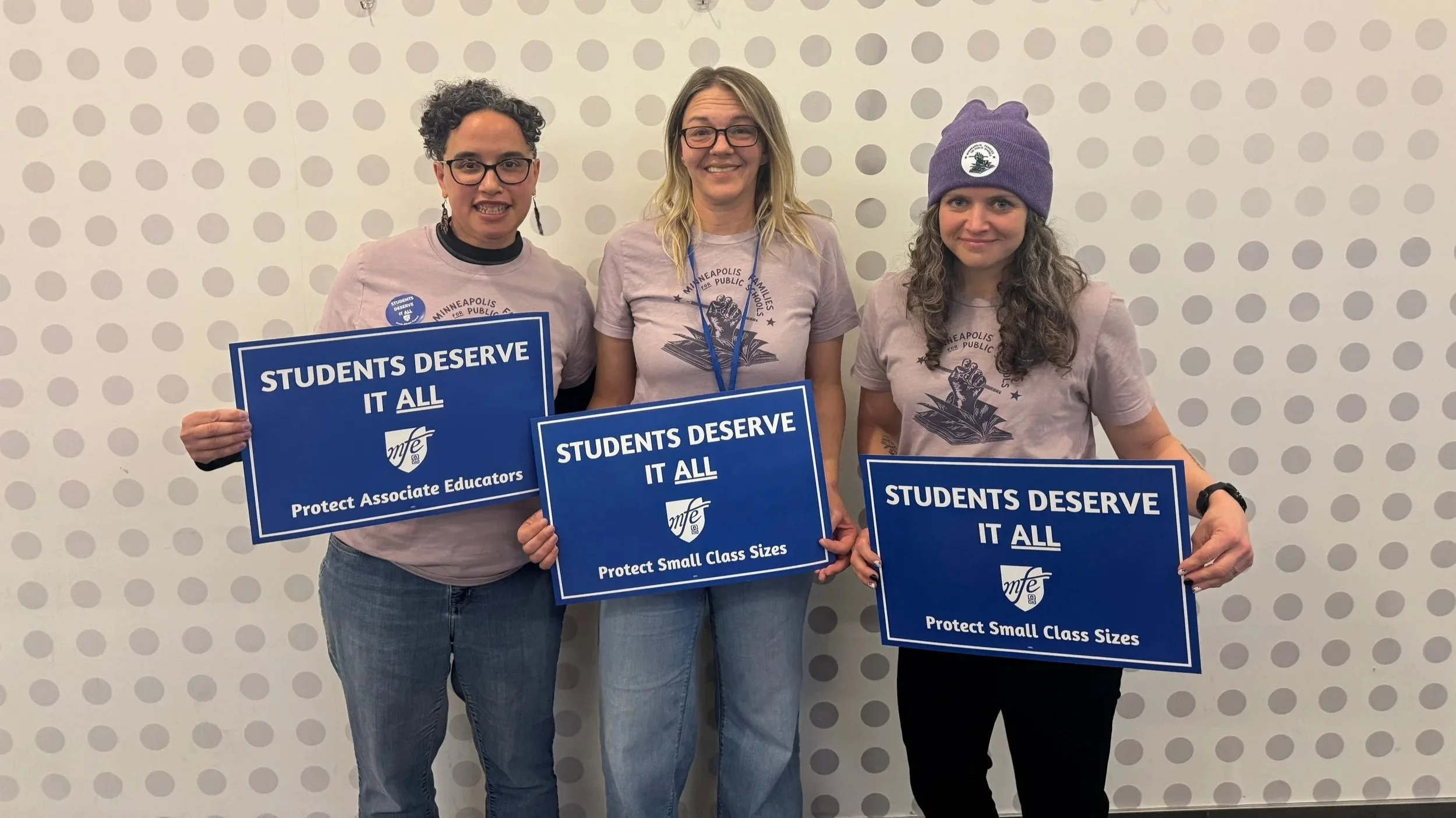 Shannon Gibney for Minneapolis School Board, District 3 standing with two other women holding signs that read "Students Deserve It All," with additional text on two signs stating "Protect Small Class Sizes."