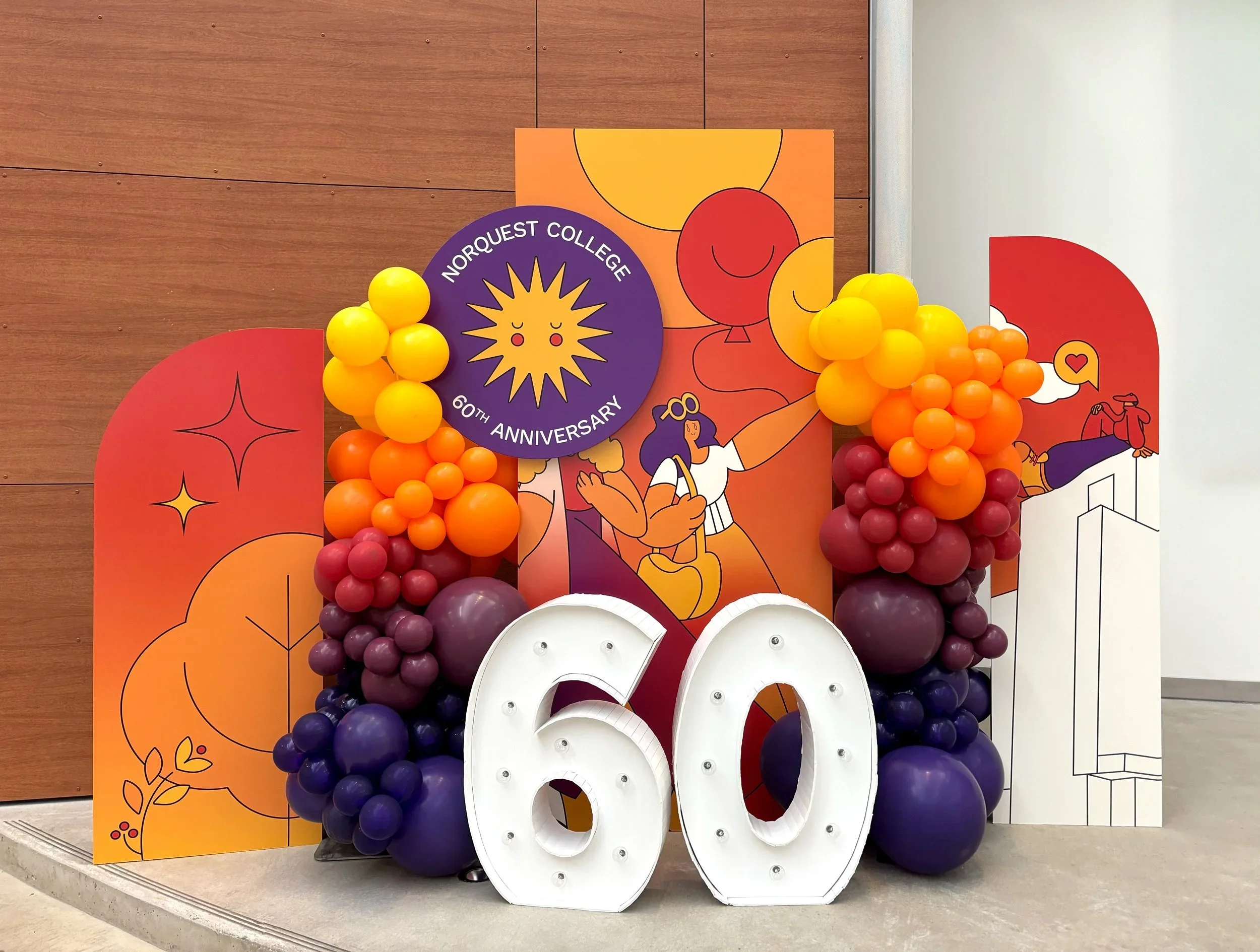 Decorative display celebrating Norquest College's 60th anniversary with balloons, colorful backgrounds, and large number '60' signs.