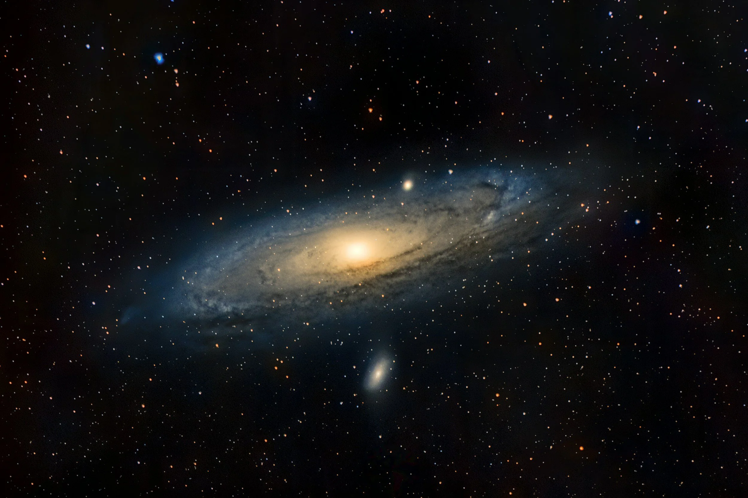 A galaxy with a bright central core surrounded by a halo of stars and cosmic dust, with additional smaller galaxies in the background, set against the dark expanse of space.